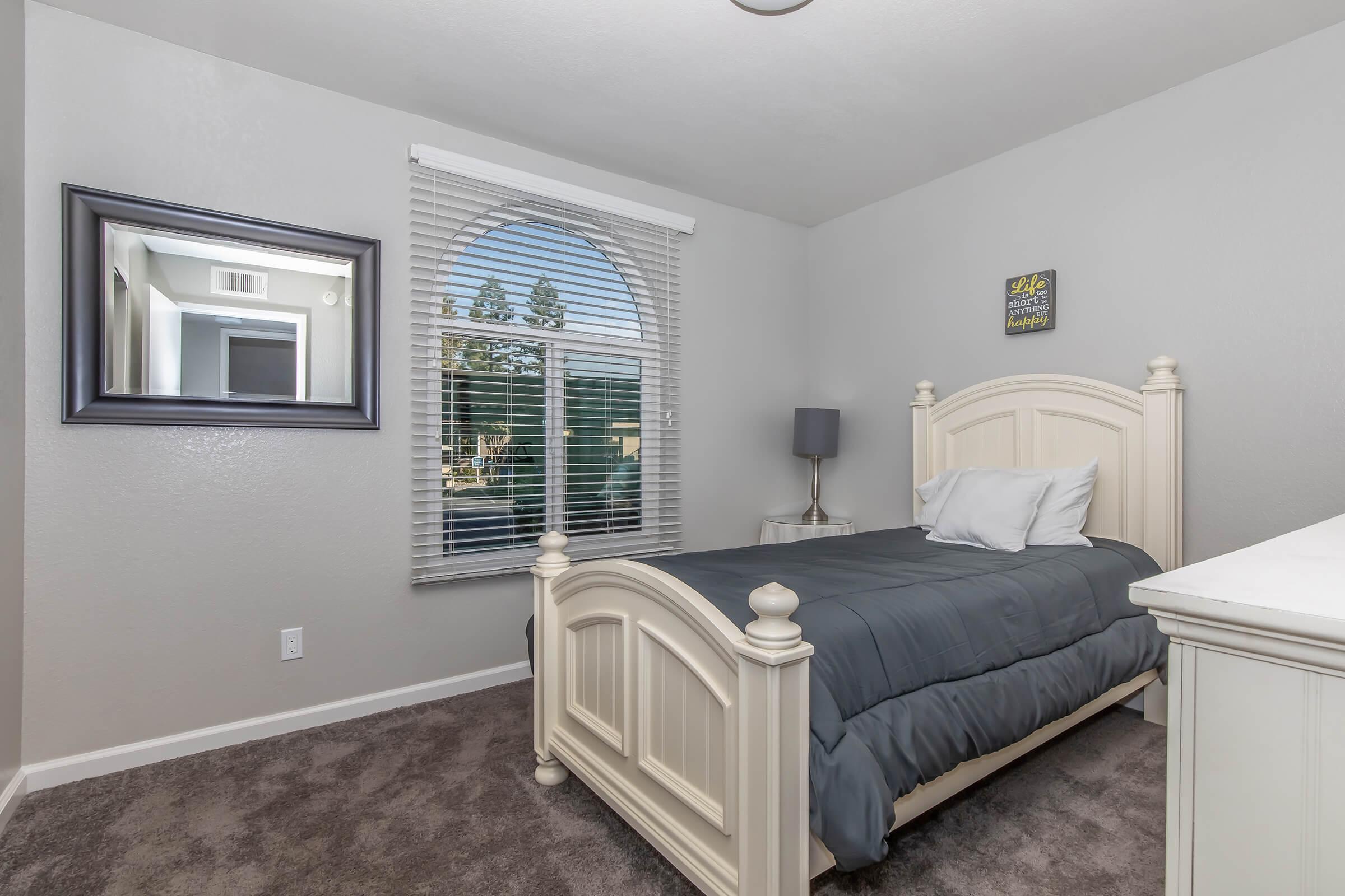 Apartments Near Sierra Vista Mall in Visalia, CA - Oak View - Bedroom with Plush Carpeting, a Large Window, and a Large Dresser