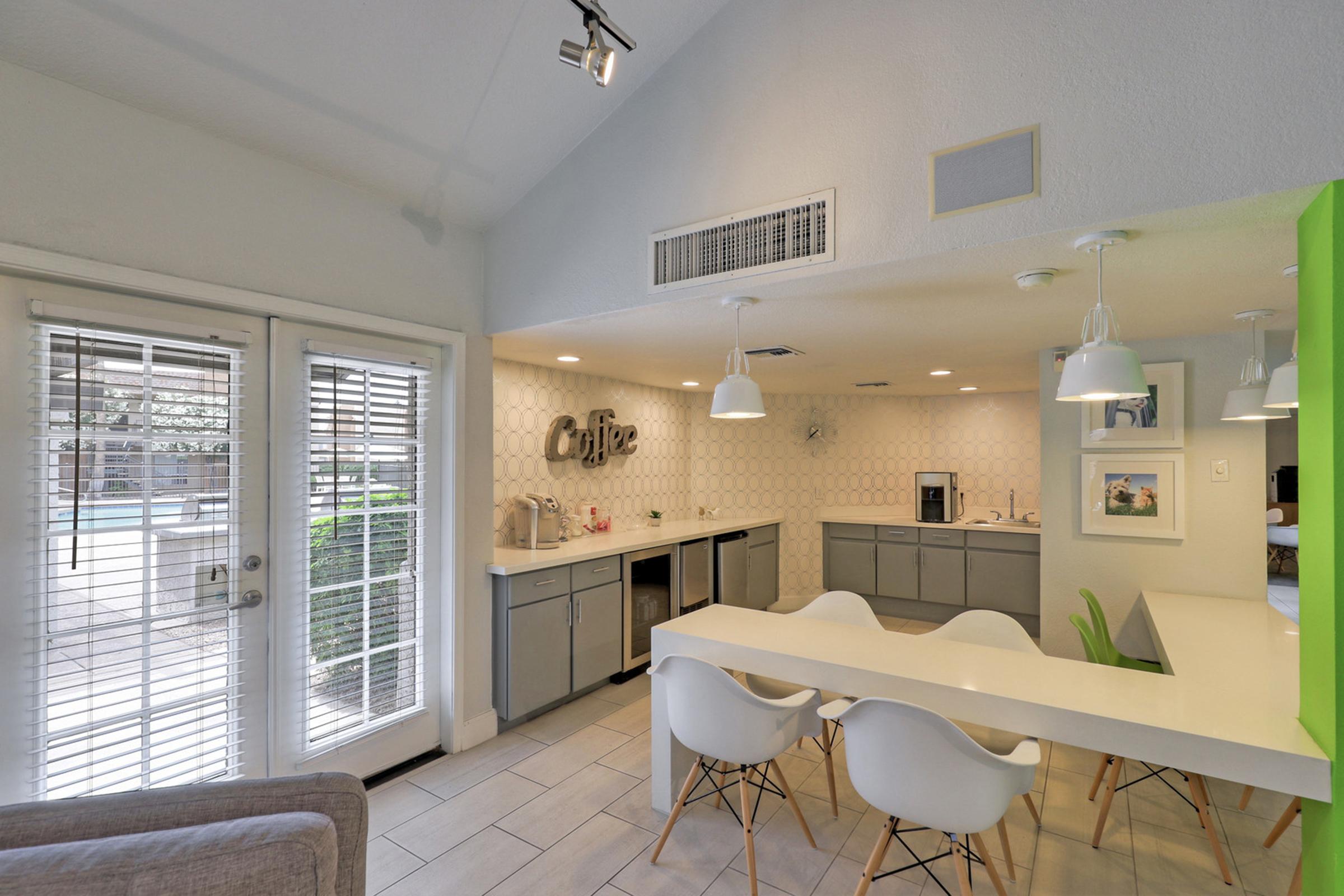 Modern kitchen featuring gray cabinetry, a white countertop, and pendant lighting.