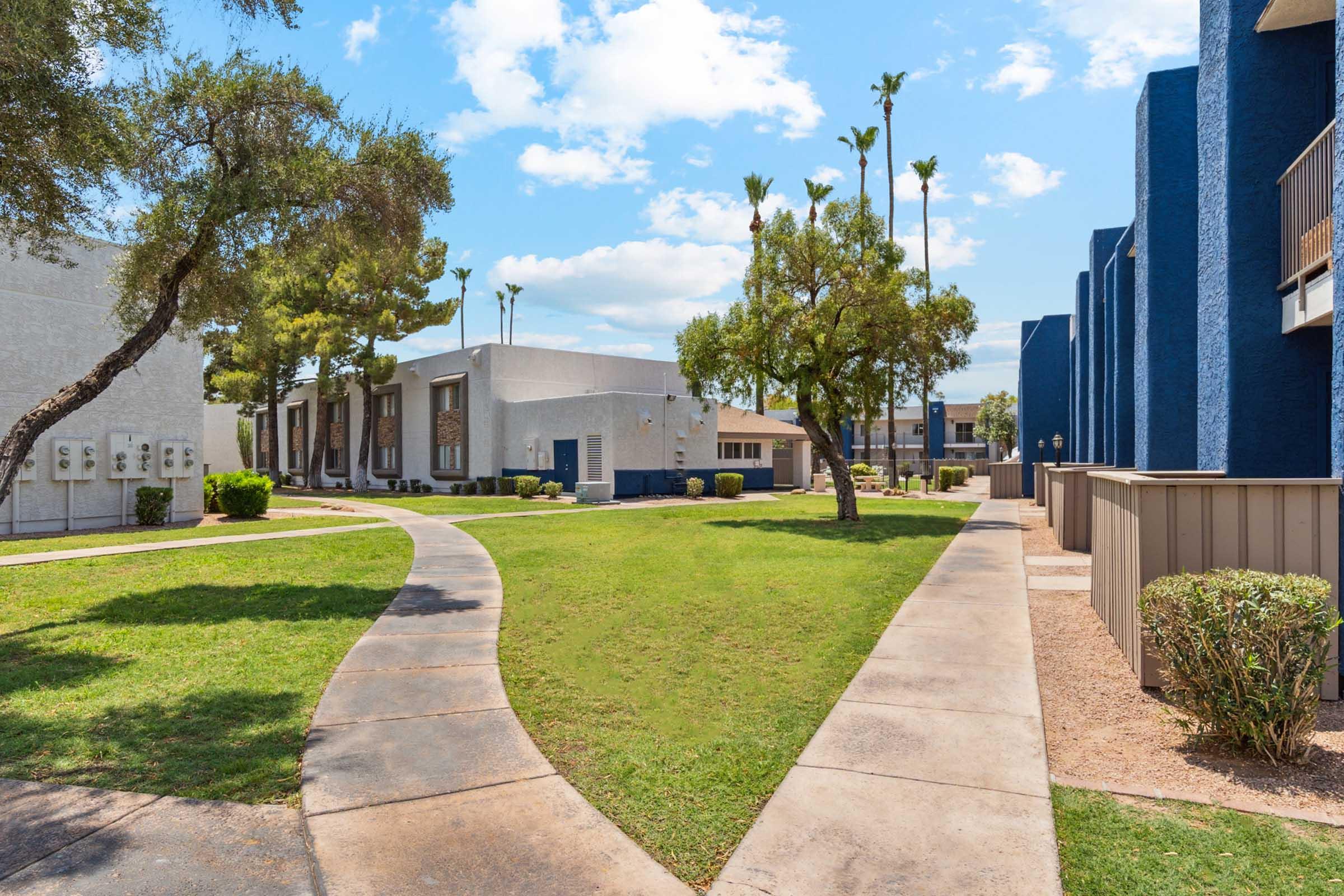 A landscaped pathway winding through an apartment complex with green lawns and