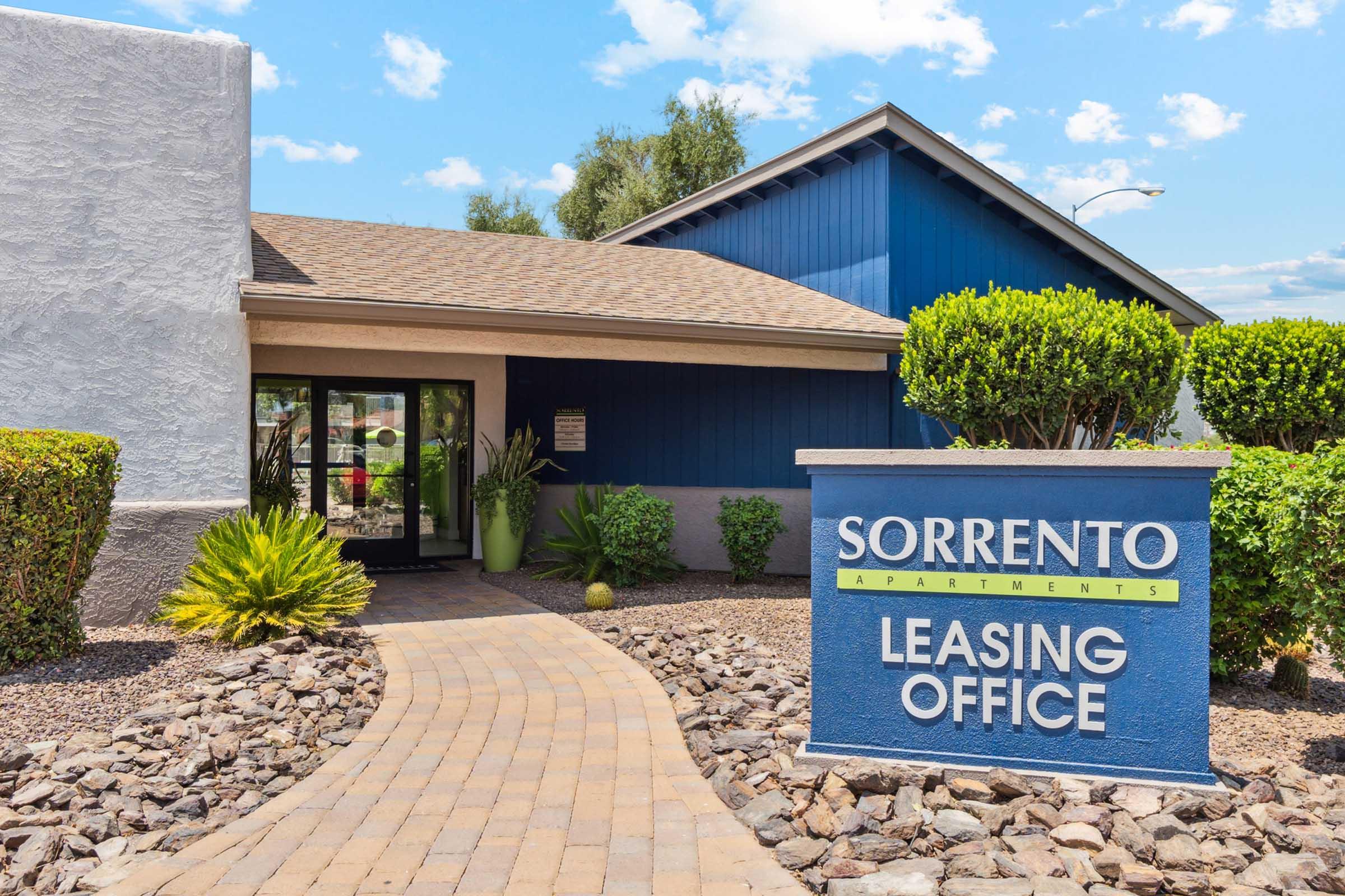A well-maintained leasing office for Sorrento Apartments, featuring a welcoming entrance with a blue exterior and landscaped greenery.