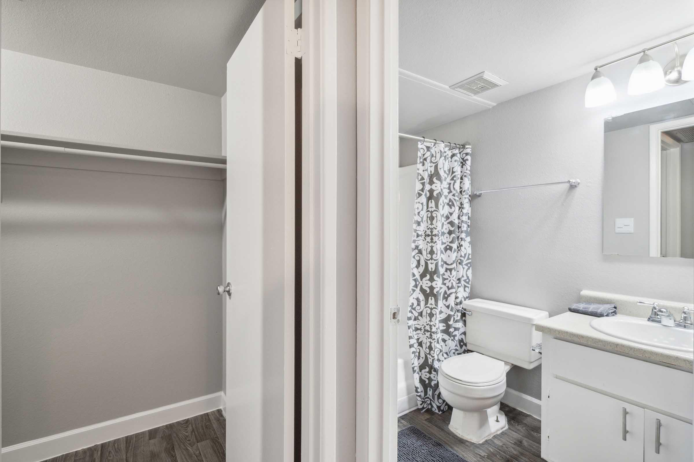 A modern bathroom featuring a toilet, sink, and a shower area with a patterned curtain.