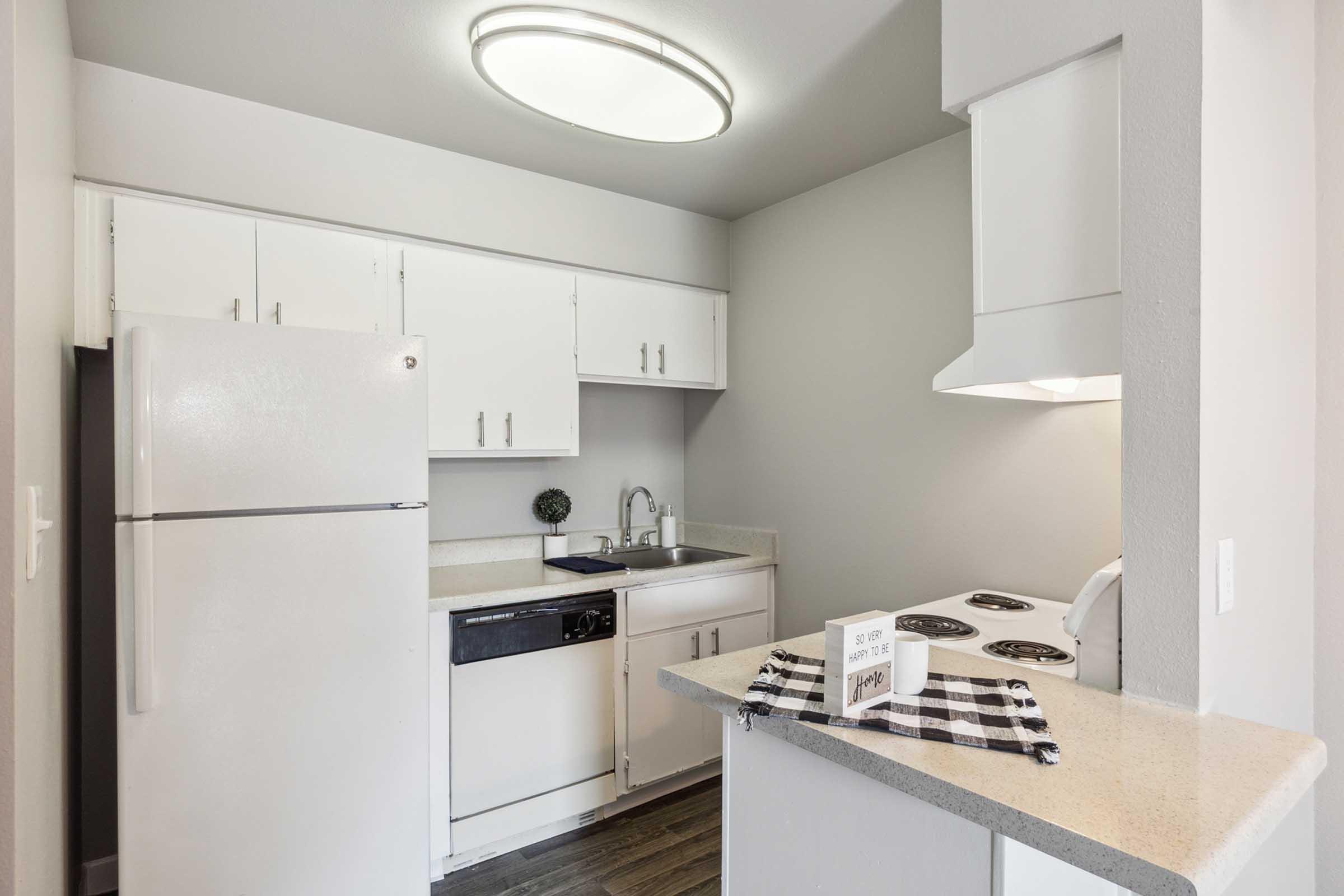 A modern kitchen featuring white cabinets, a stainless steel dishwasher, a white refrigerator, and a stove.