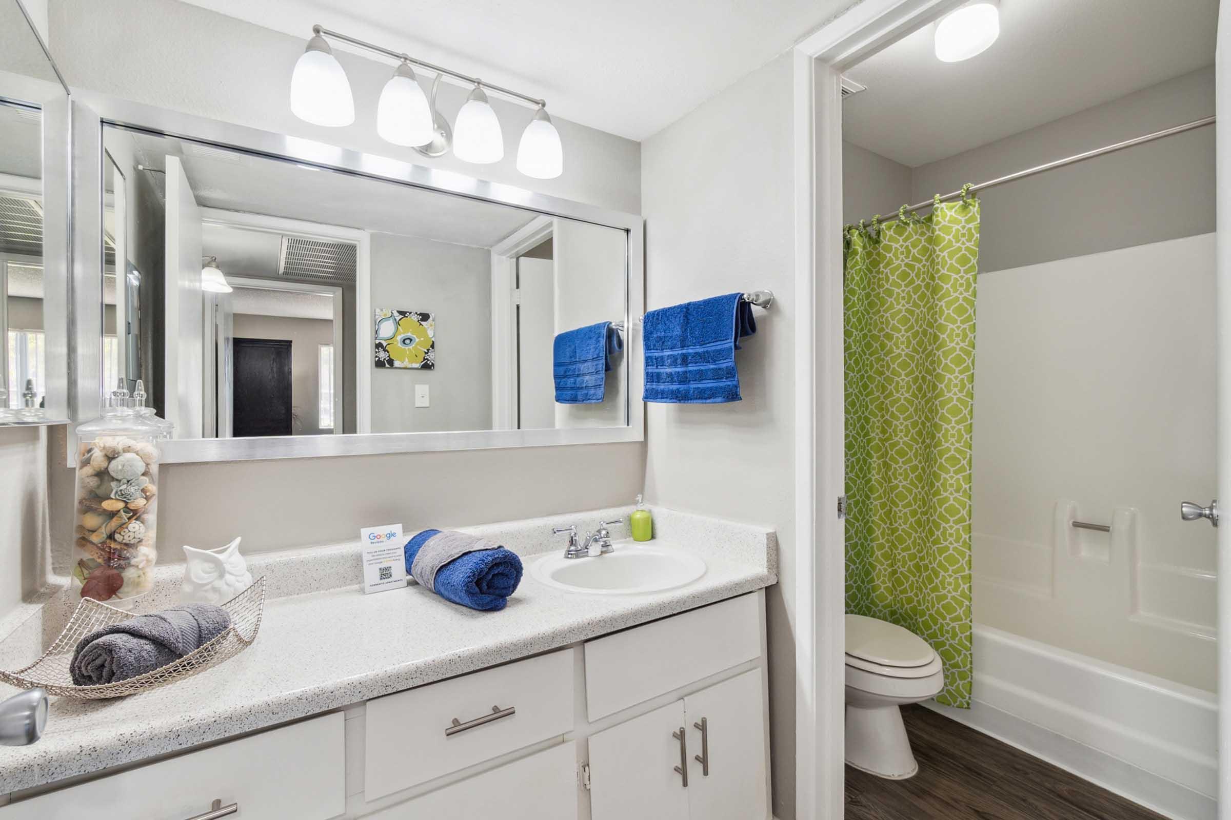 Bright, modern bathroom featuring a white countertop with neatly placed towels and toiletries.