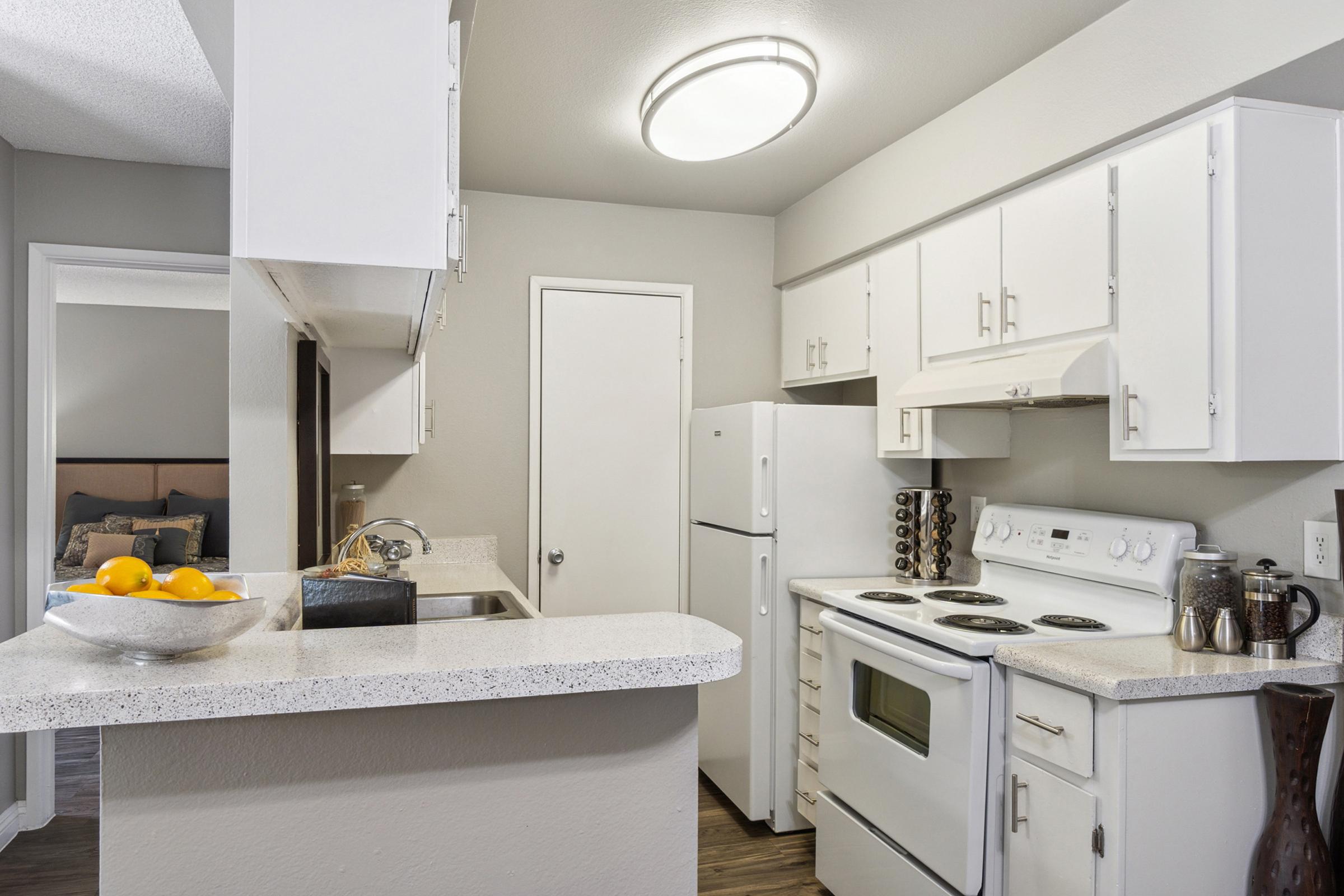 A modern kitchen featuring white cabinetry, a refrigerator, an oven, and a sink.