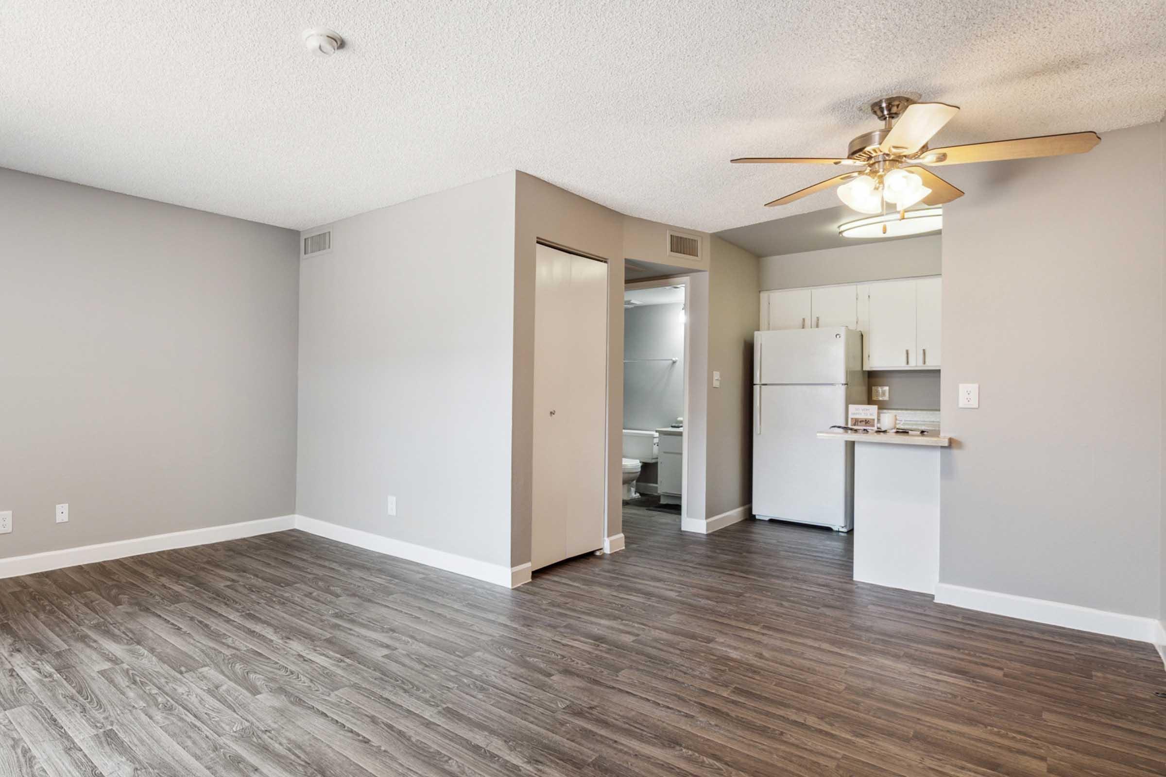 A spacious, modern living area with light gray walls and dark wood laminate flooring.