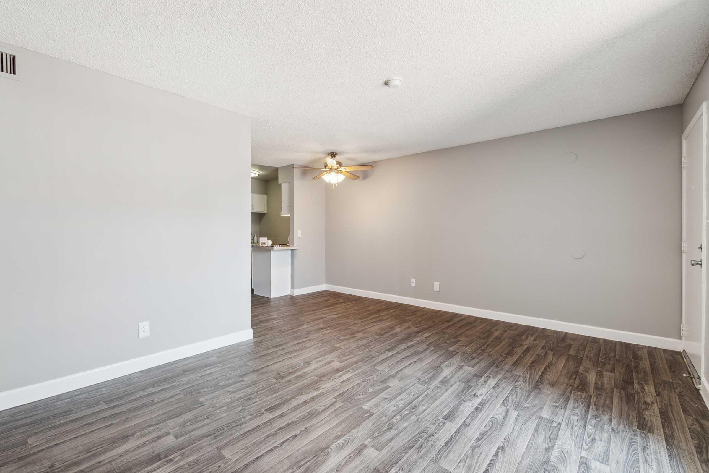 Empty living room with light gray walls and a ceiling fan.