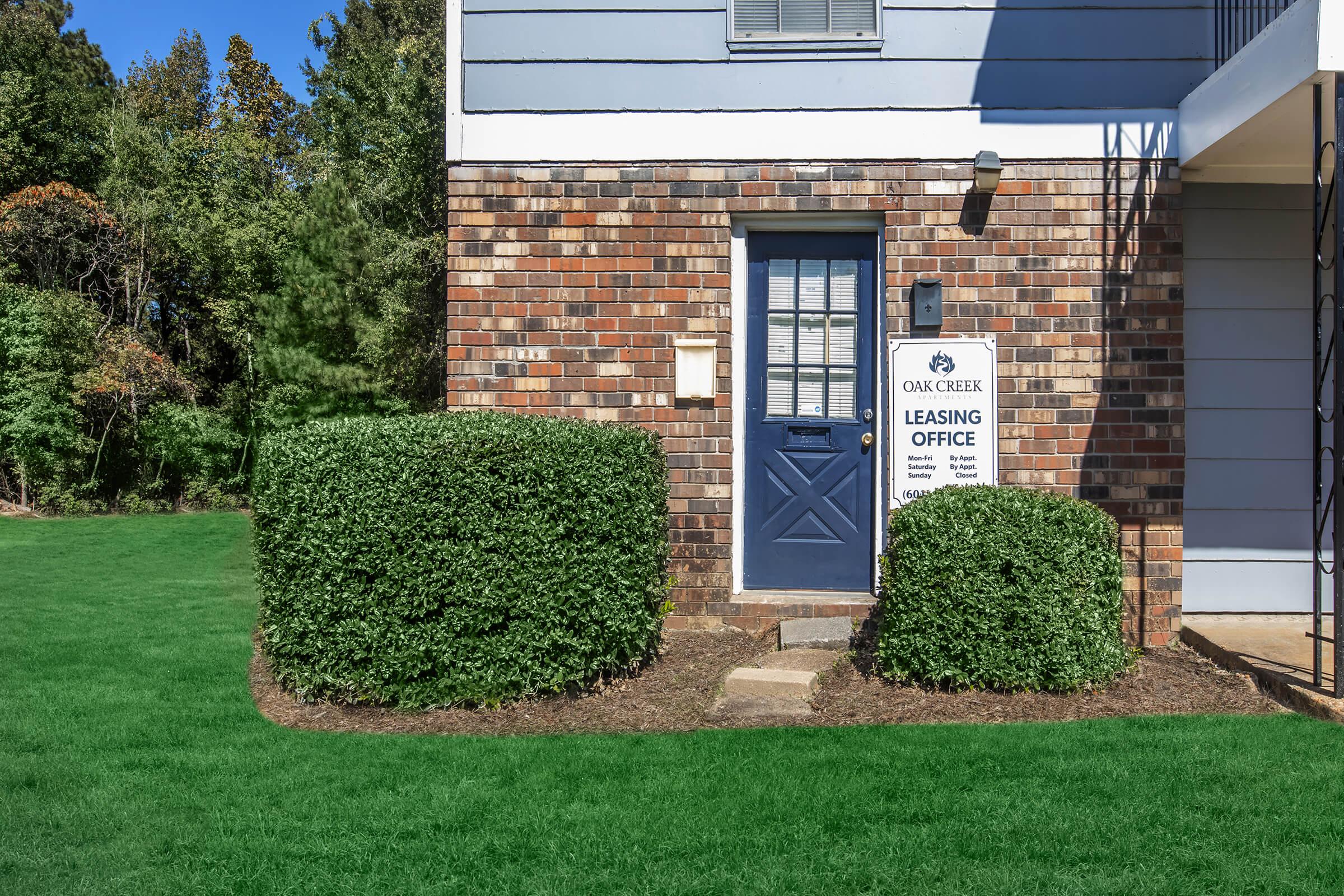 a large brick building with green grass in front of a house