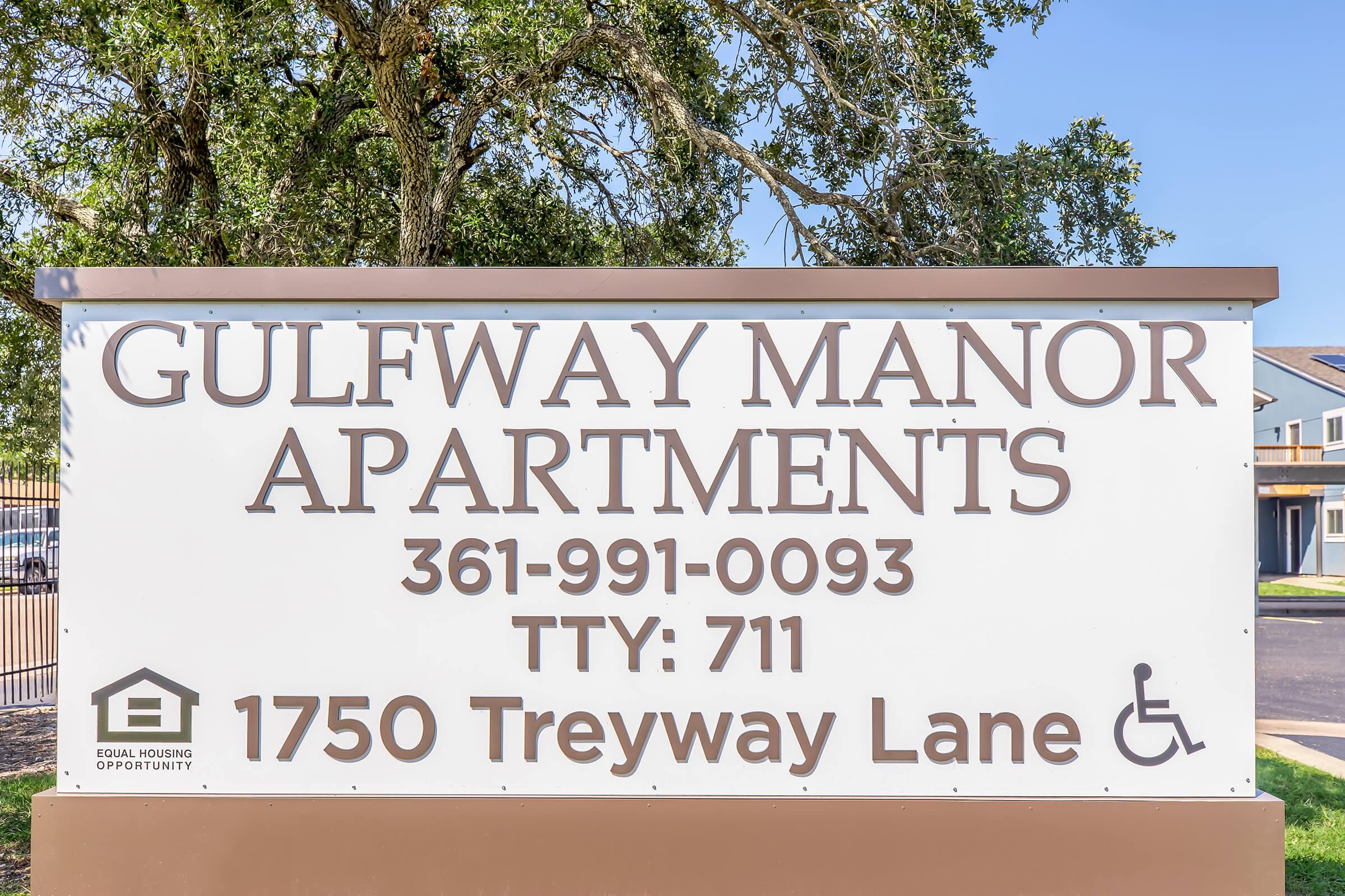 Sign for Gulfway Manor Apartments, displaying the phone number 361-991-0093, TTY number 711, and the address 1750 Treyway Lane. Includes a symbol for accessible housing and mentions Equal Housing Opportunity.