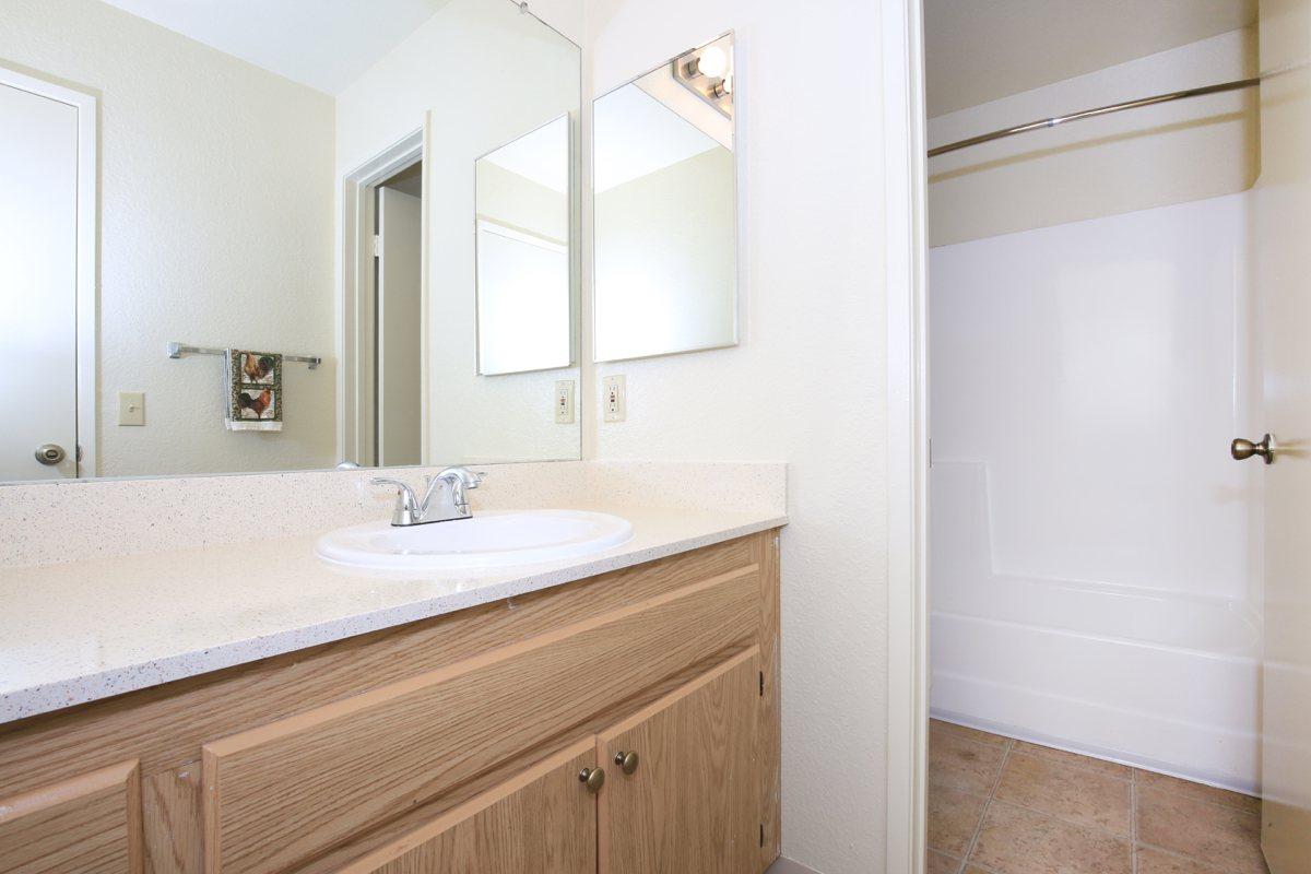 a white sink sitting under a mirror