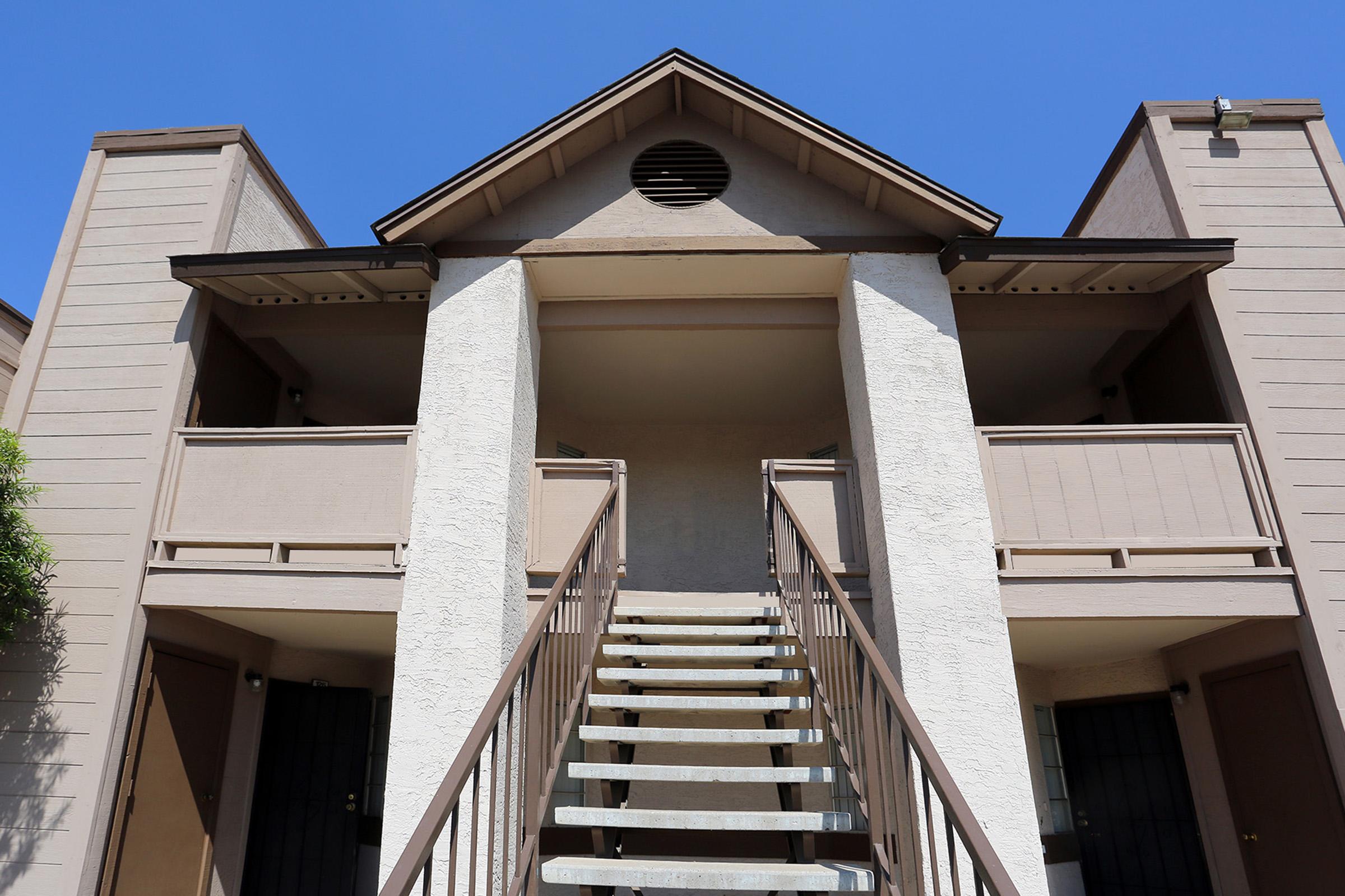 A view of an apartment building's entrance, featuring two sets of stairs leading up to the second floor.