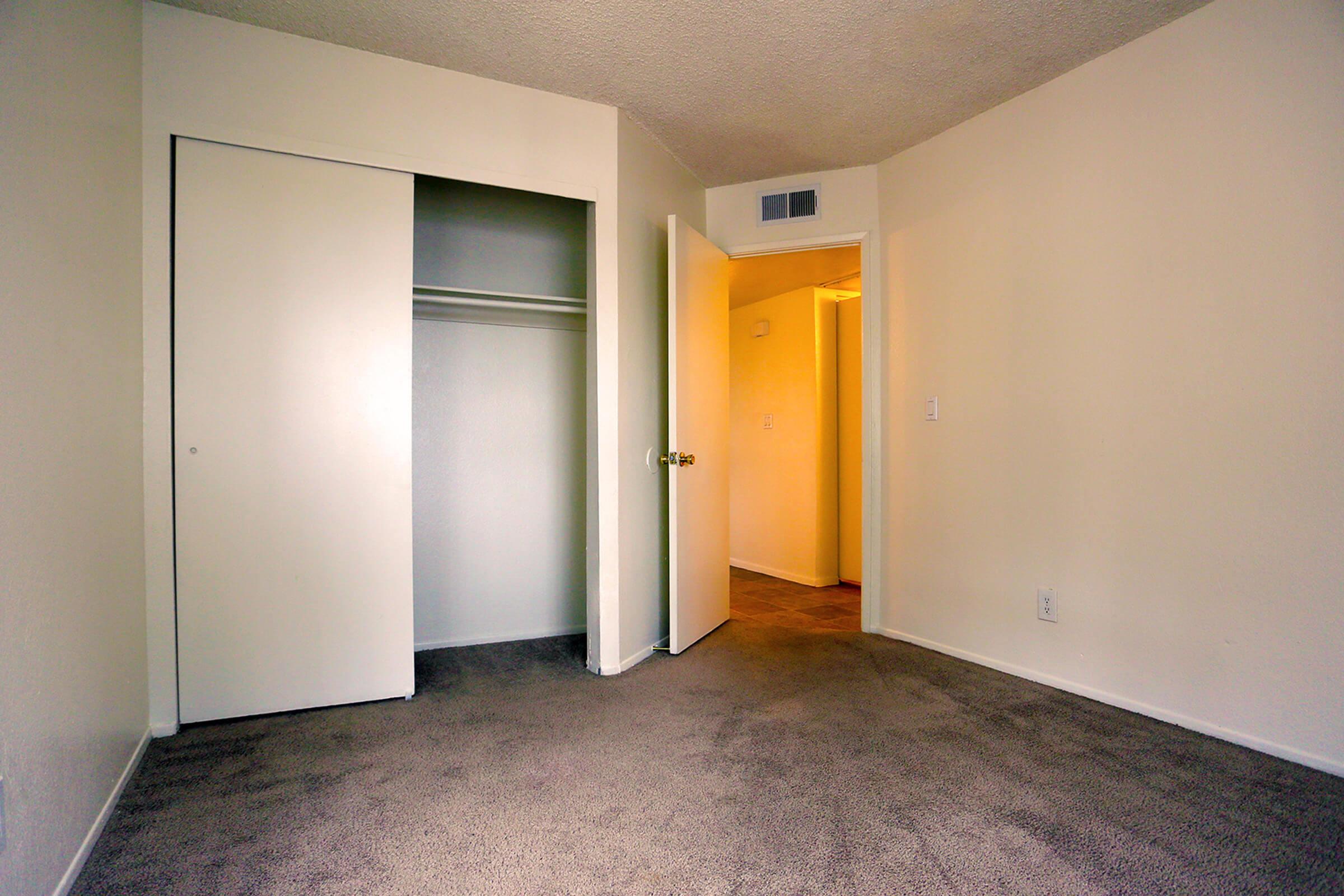 A vacant room with beige walls and a light brown carpet. T