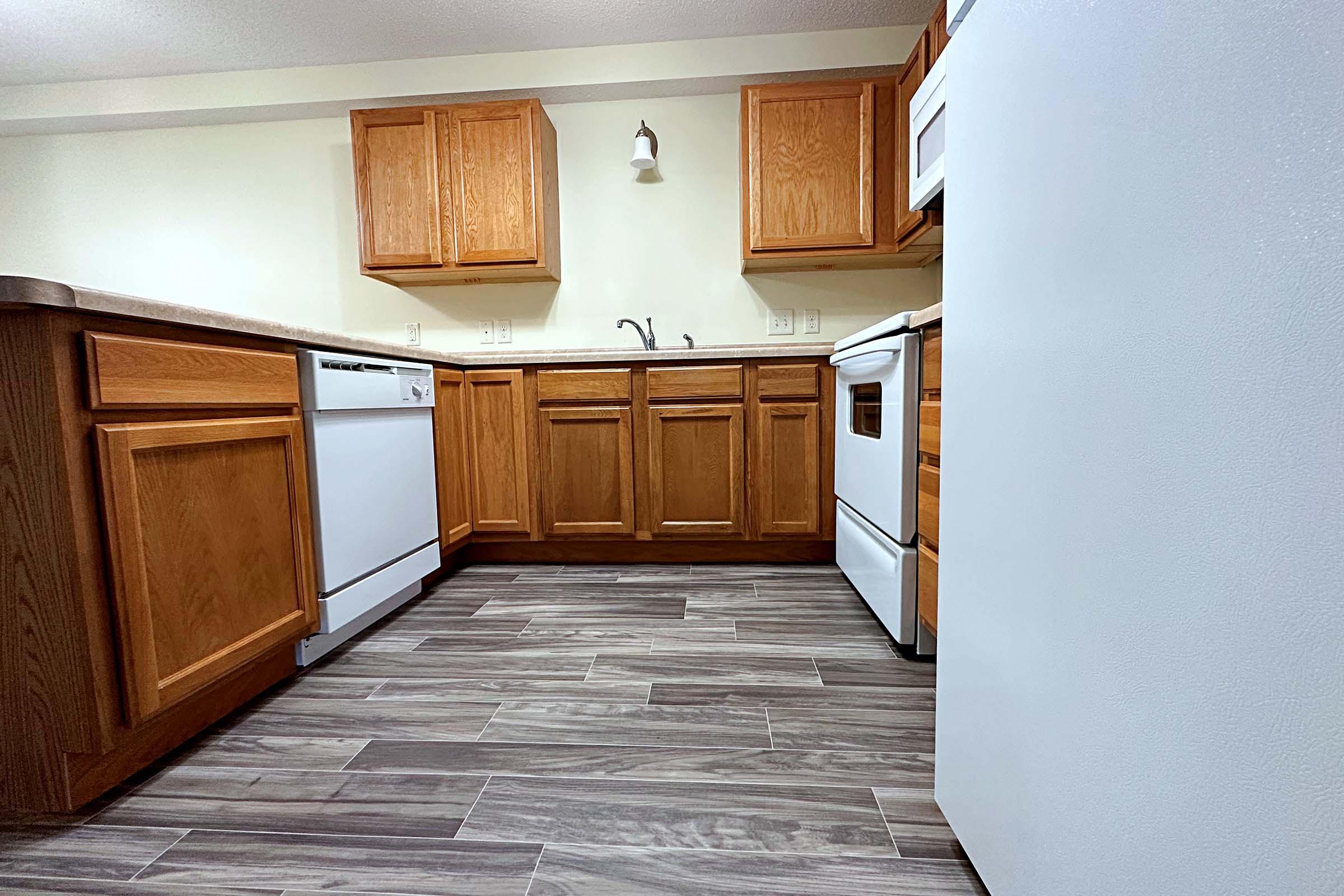 a kitchen with wooden cabinets and a wood floor