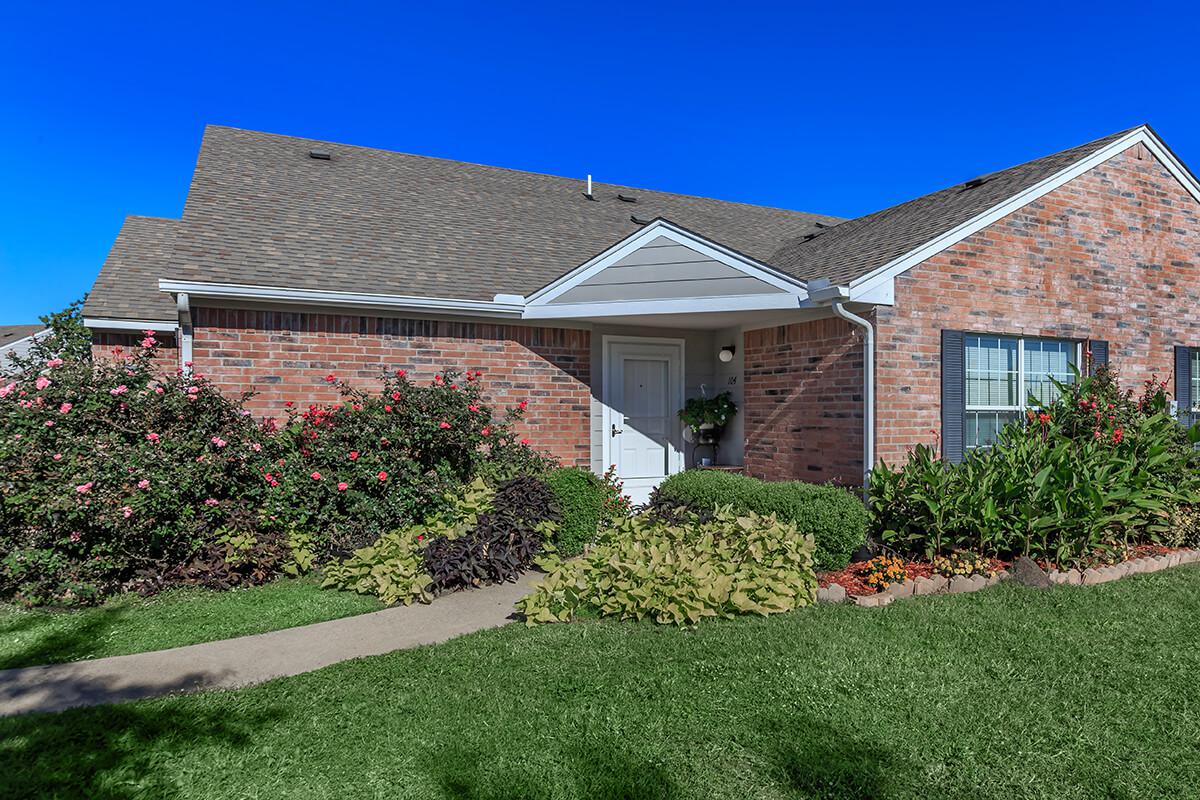 a large brick building with grass in front of a house