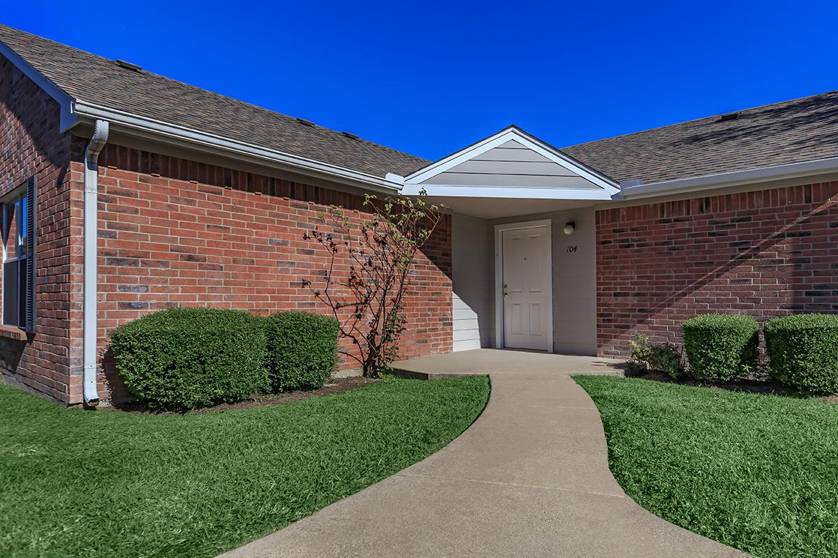 a large brick building with grass in front of a house