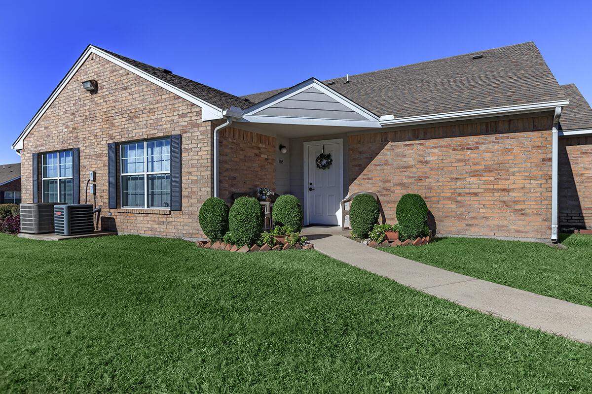 a large brick building with grass in front of a house