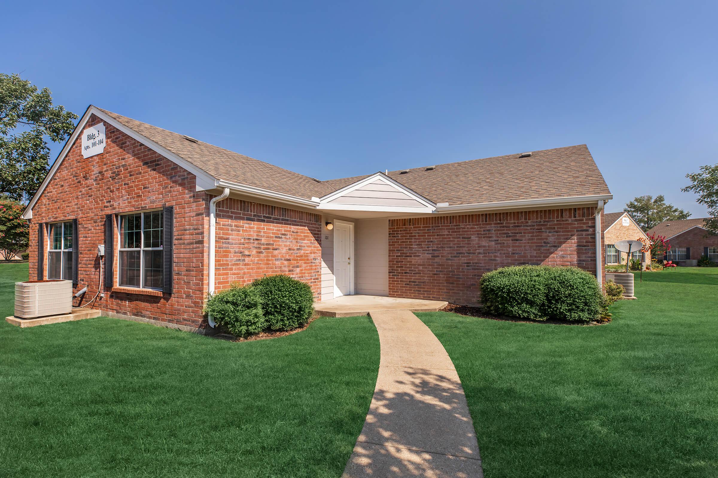 a large brick building with green grass in front of a house