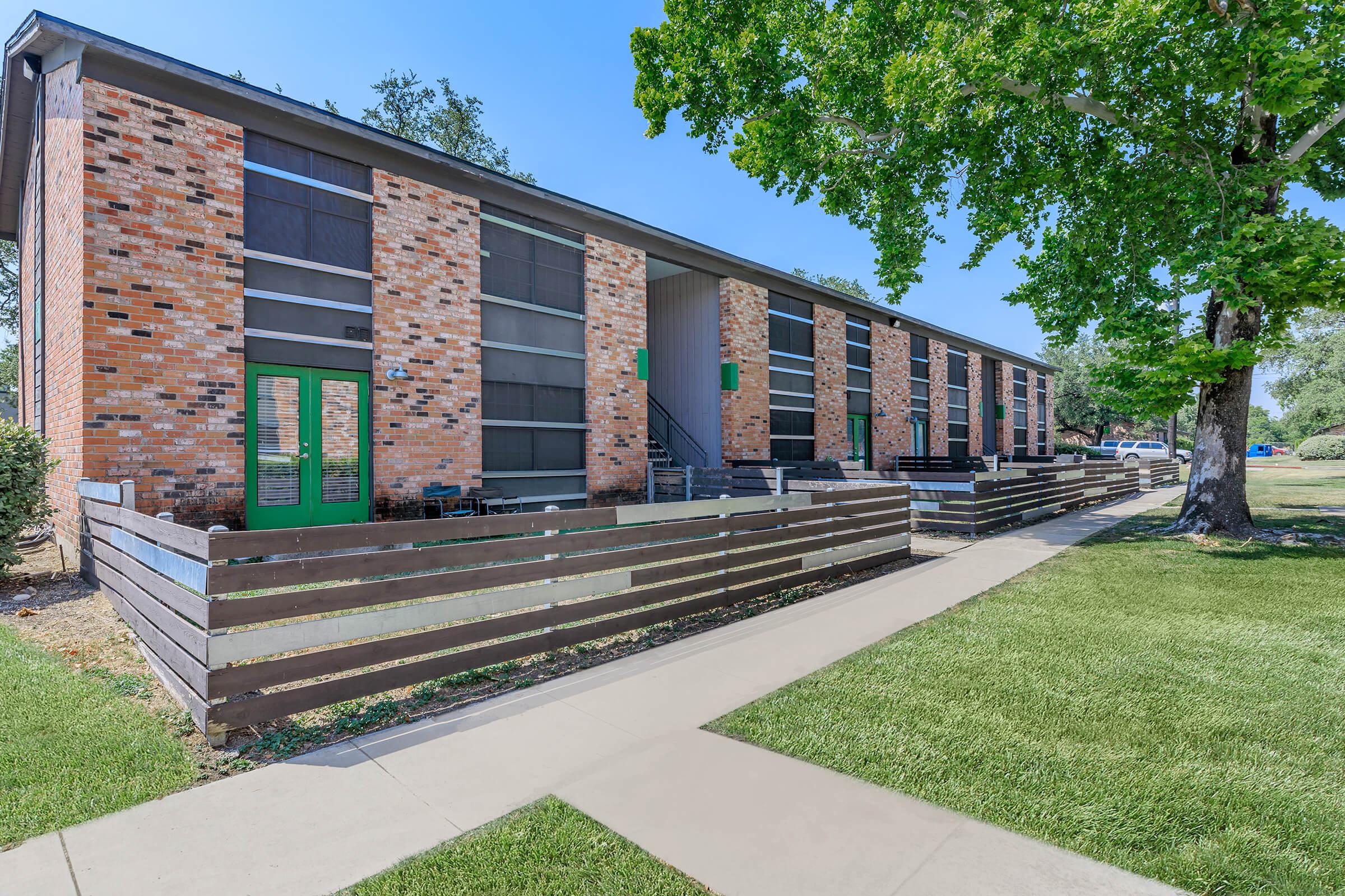 a large brick building with grass and trees