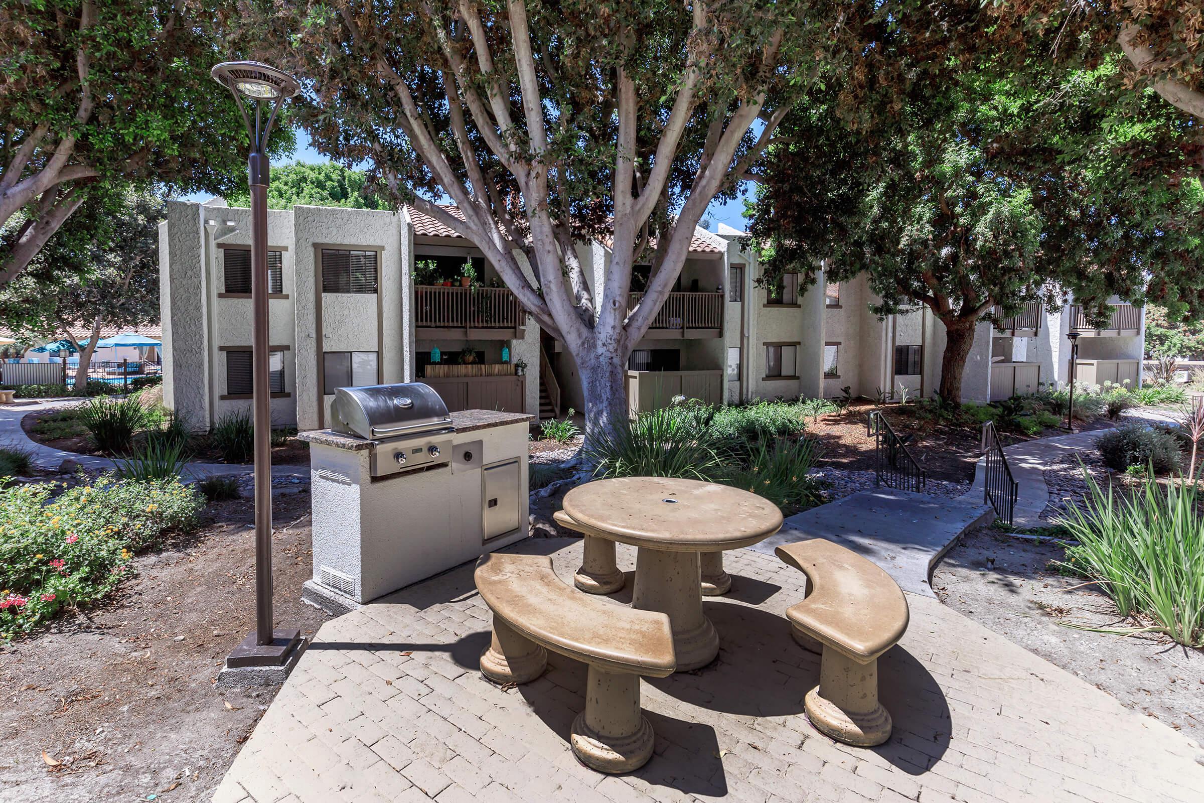 a statue of a cement bench sitting next to a tree