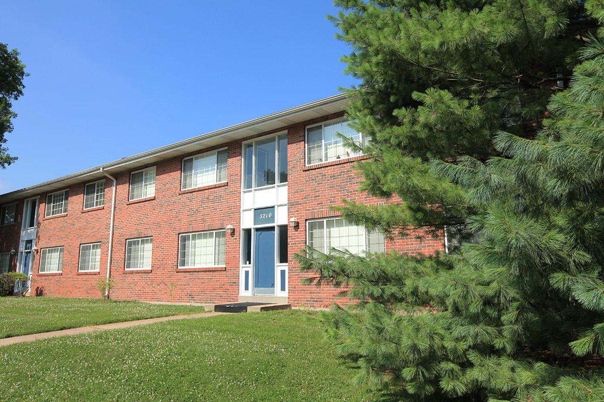 a large brick building with grass in front of a house