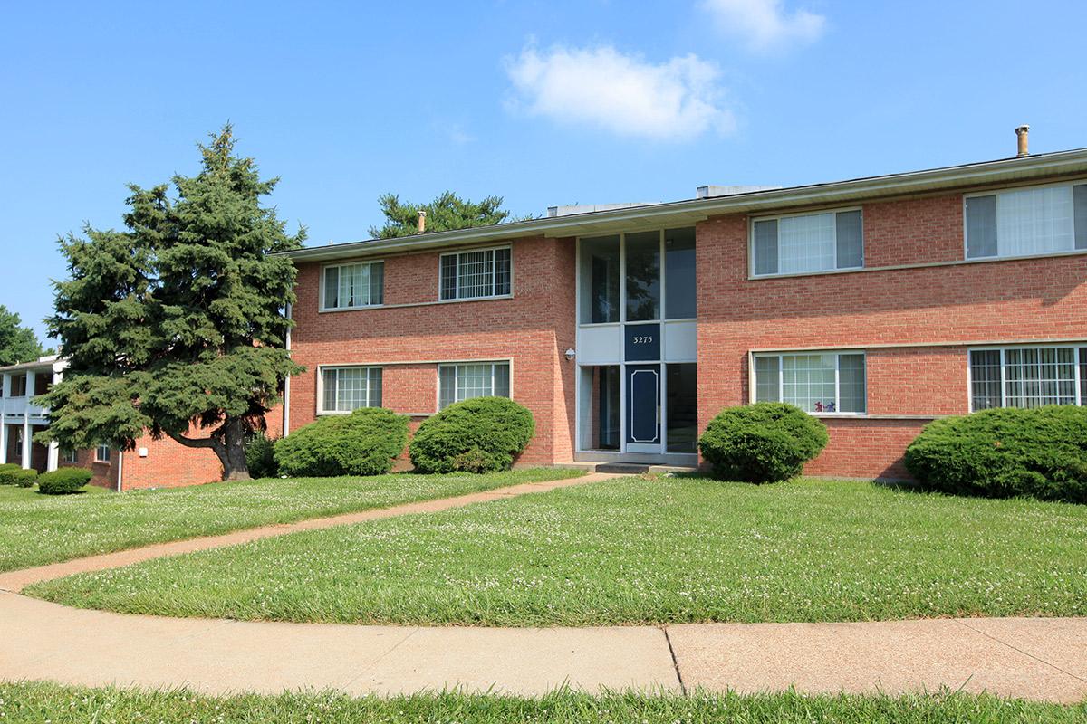 a house with a lawn in front of a brick building