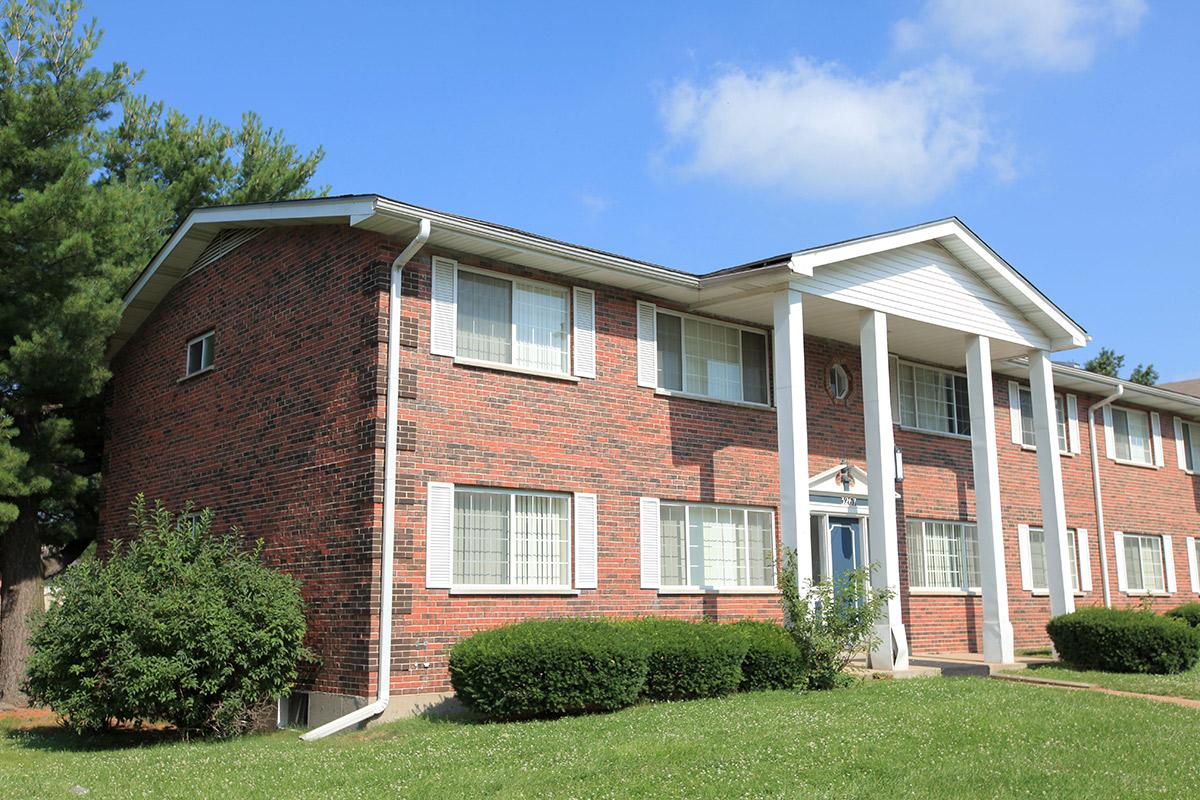 a large brick building with grass in front of a house