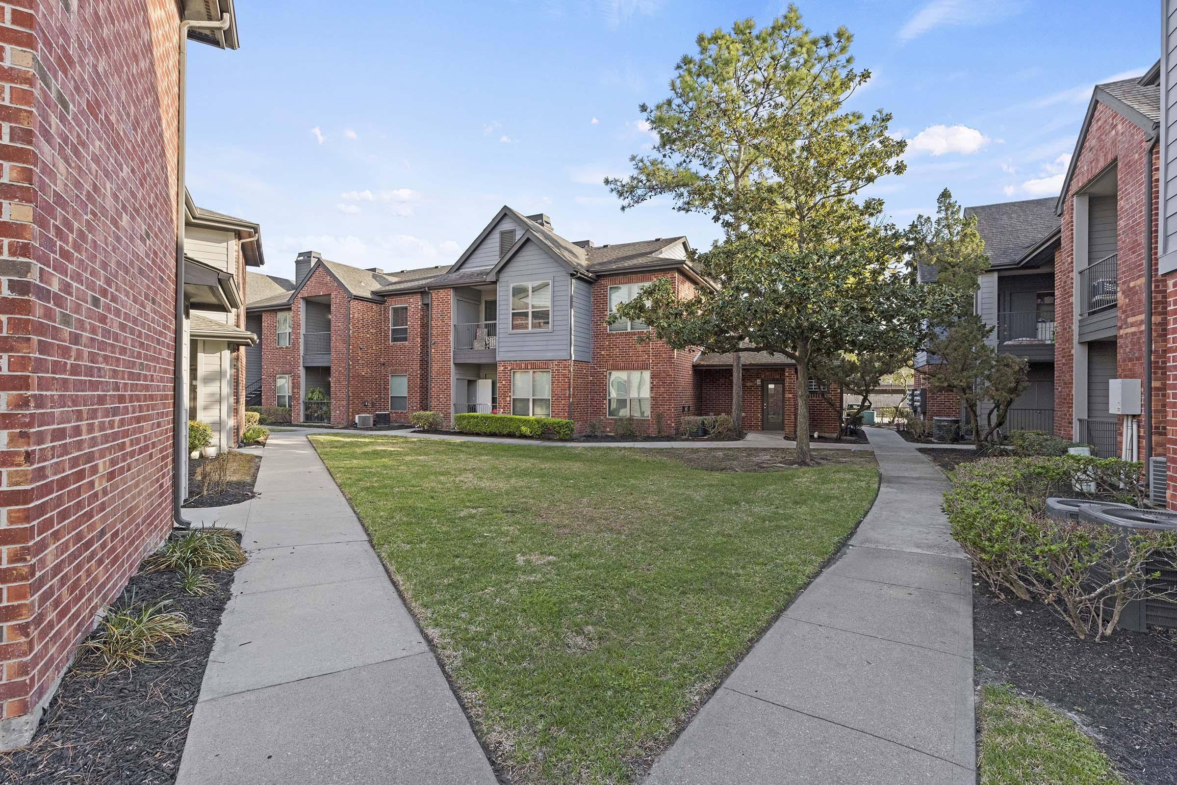 a large brick building with grass in front of a house