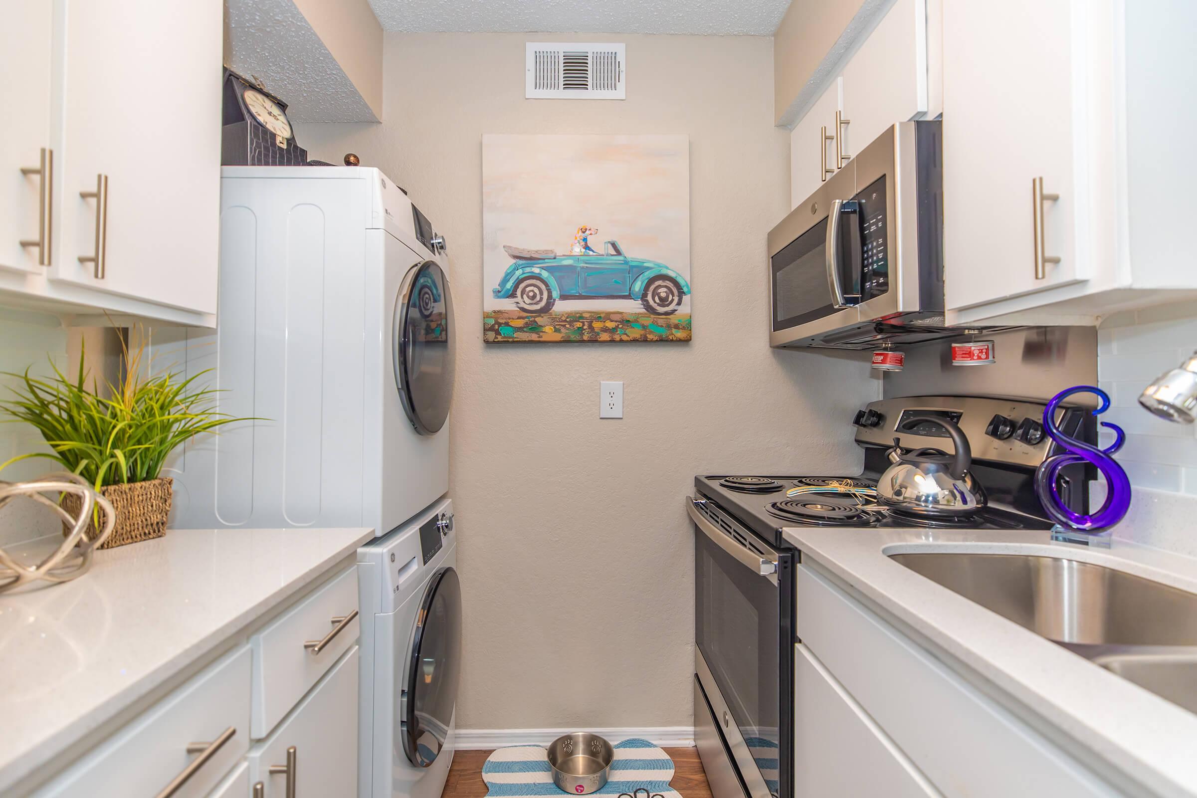 A model apartment kitchen with white cabinets and a washer and dryer at Rise Oak Creek.