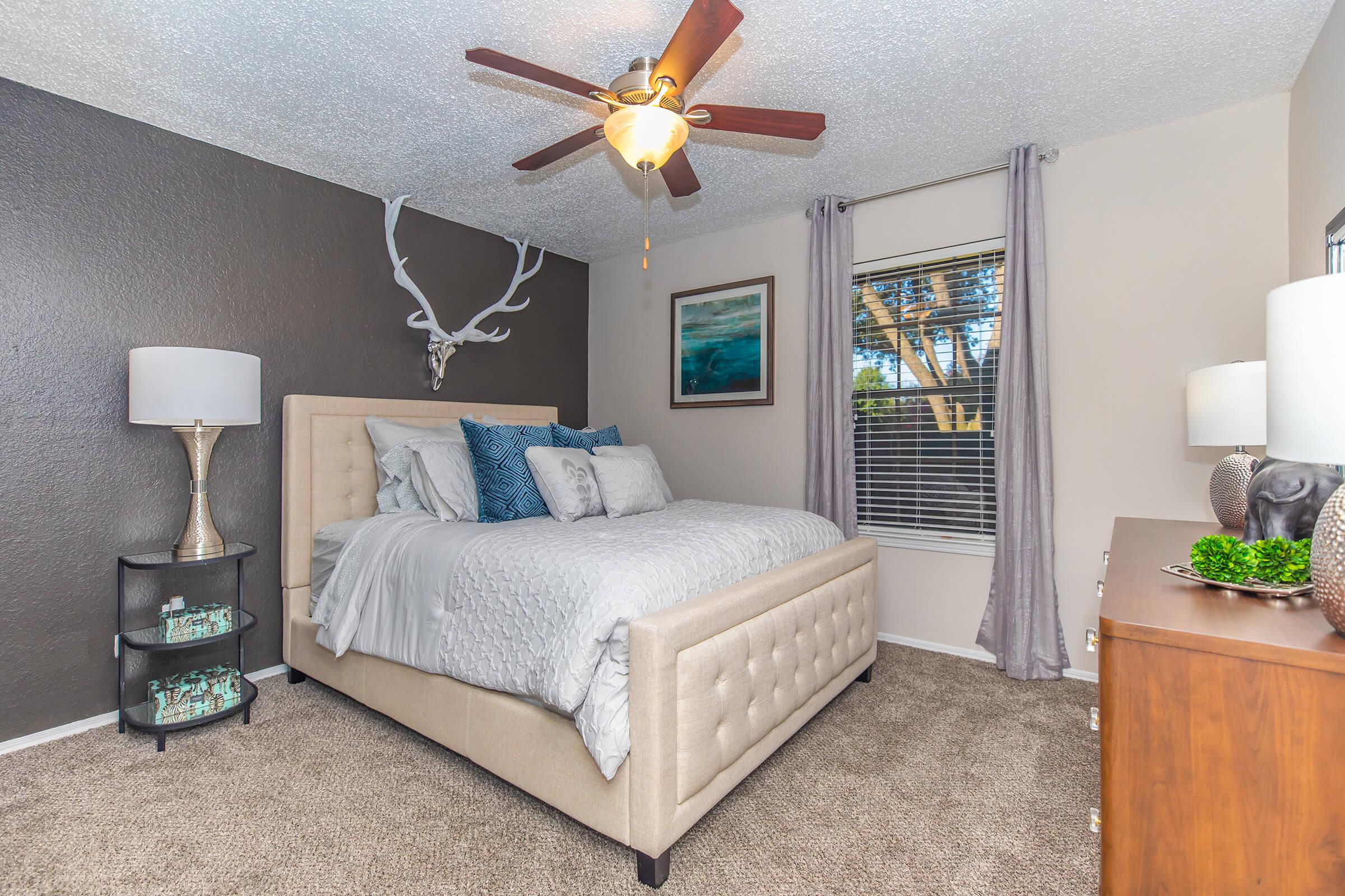 A bedroom with carpeting, a window, a queen bed and a dresser at Rise Oak Creek.