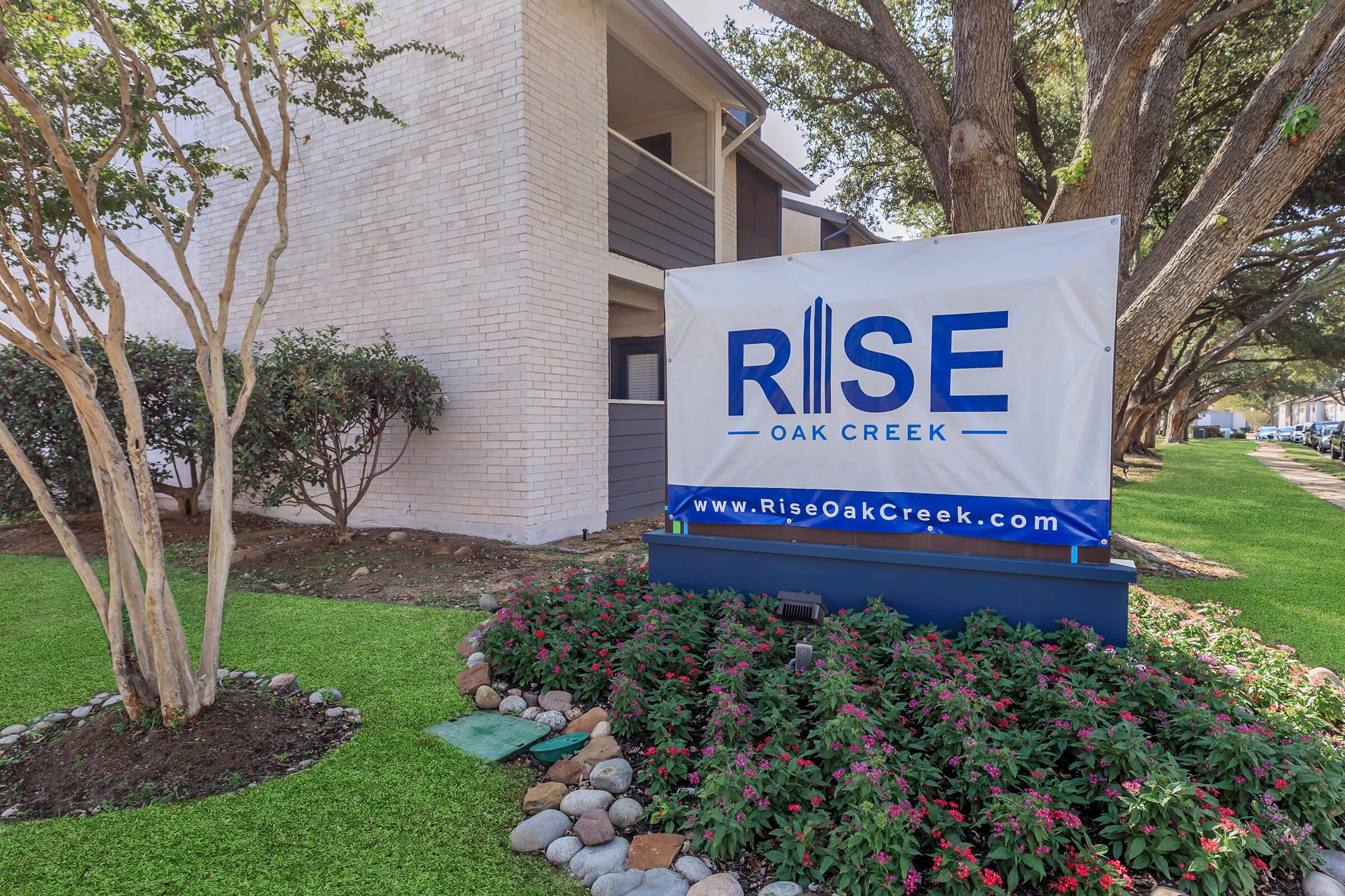 The Rise Oak Creek entrance signage surrounded by foliage.