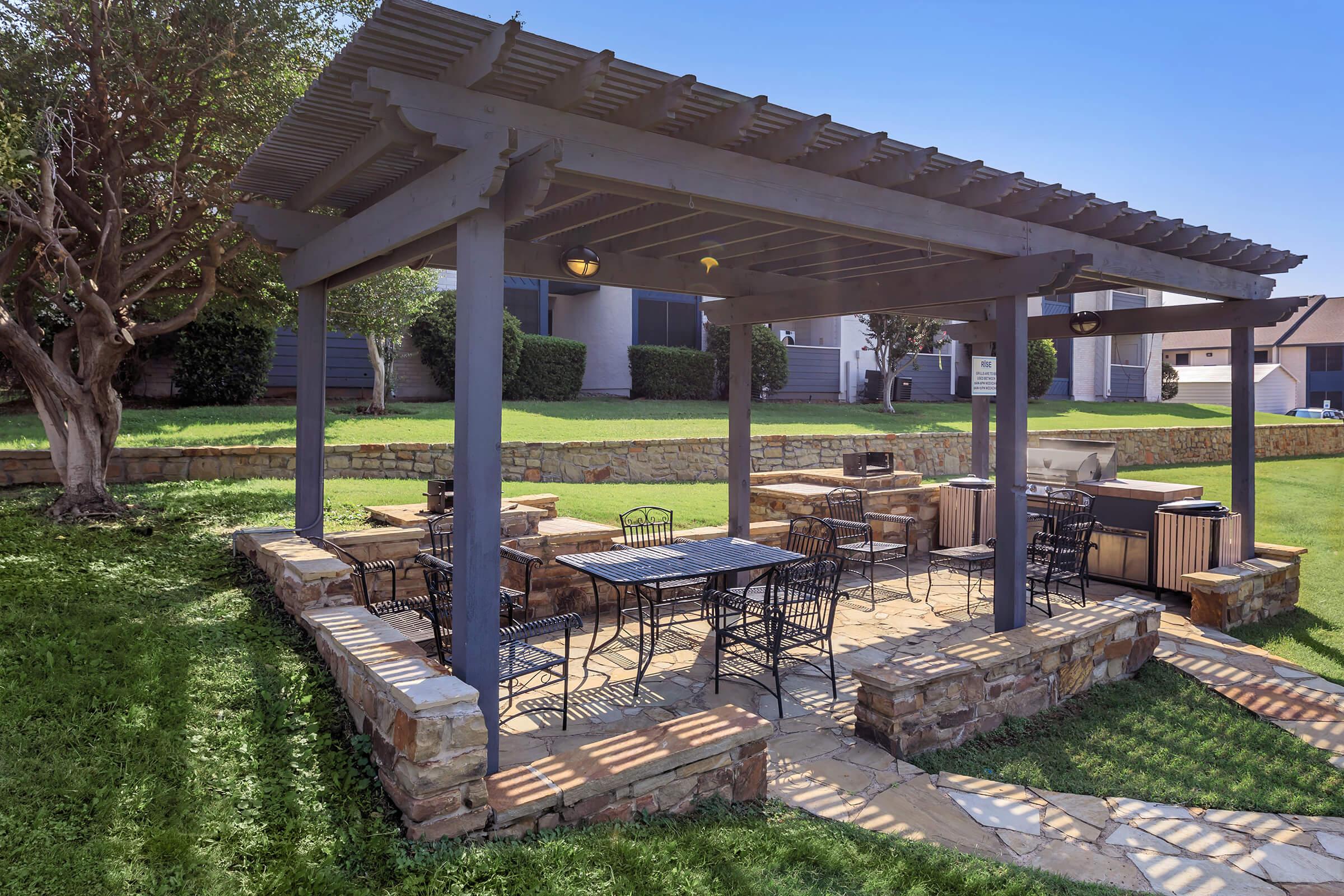 A grilling area with table and chairs in the landscaped courtyard at Rise Oak Creek.
