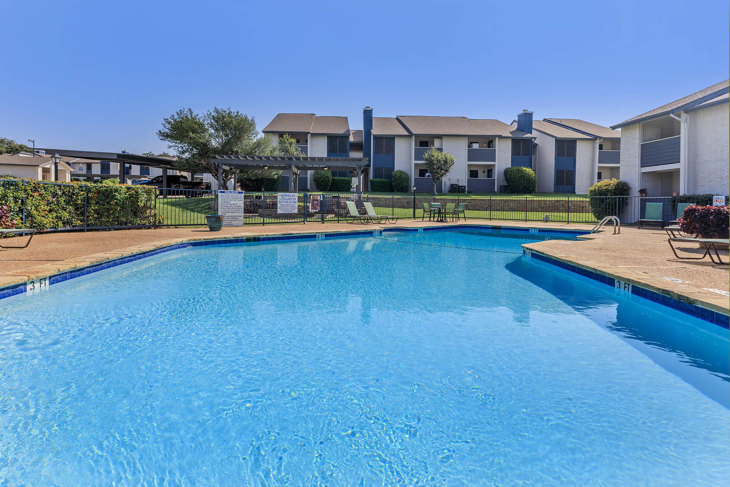 Rise Oak Creek's large dazzling pool with loungers surrounded by the apartments.