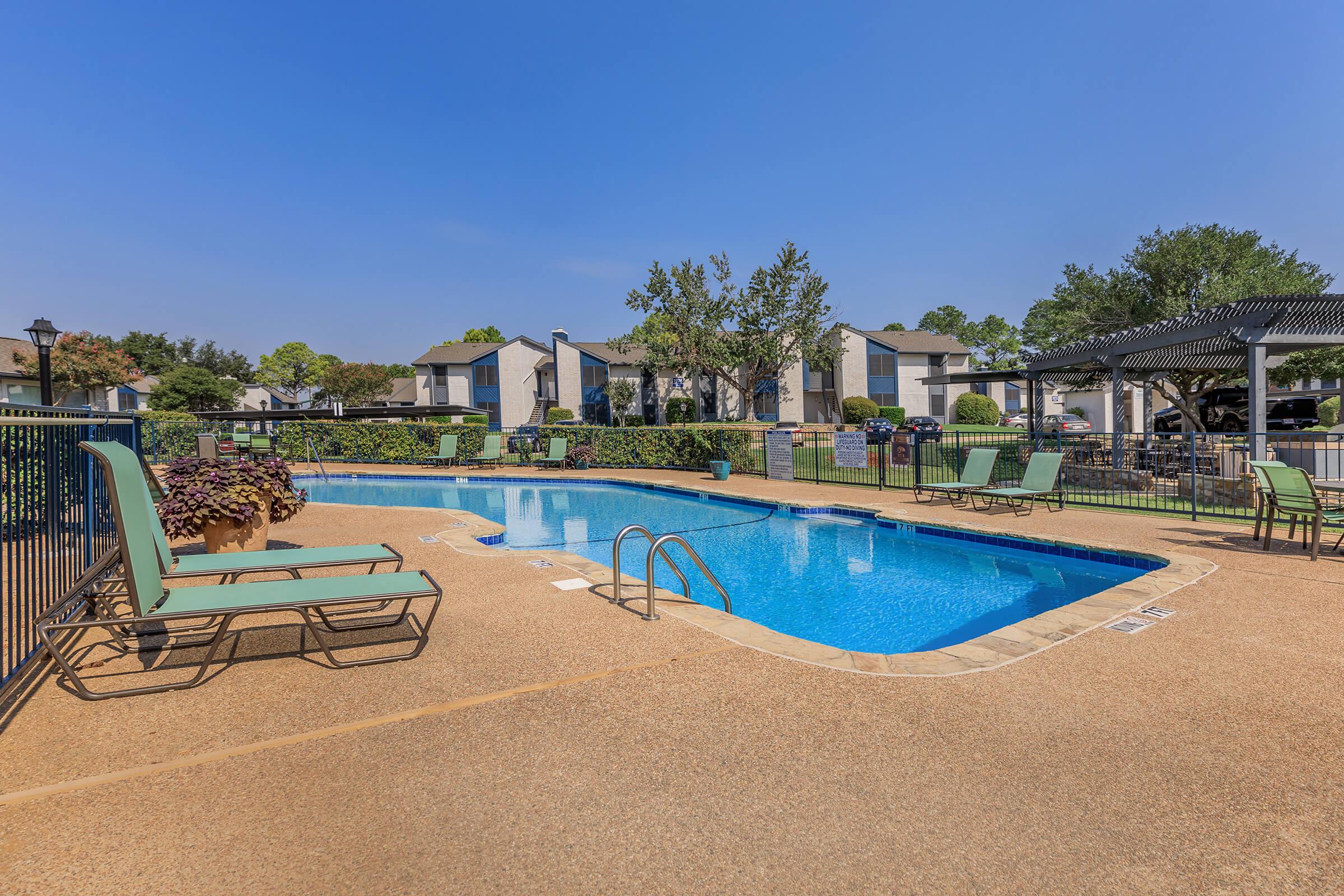 A resort-style pool surrounded by foliage and loungers at Rise Oak Creek.