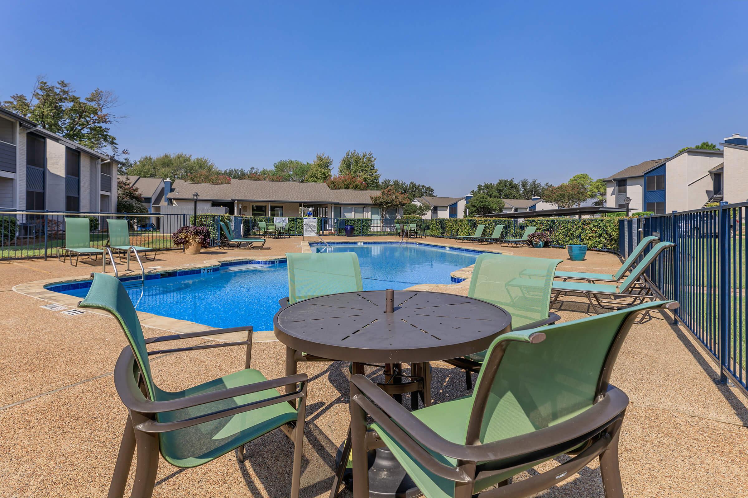Table and chairs surrounding the dazzling pool at Rise Oak Creek in Bedford, TX.