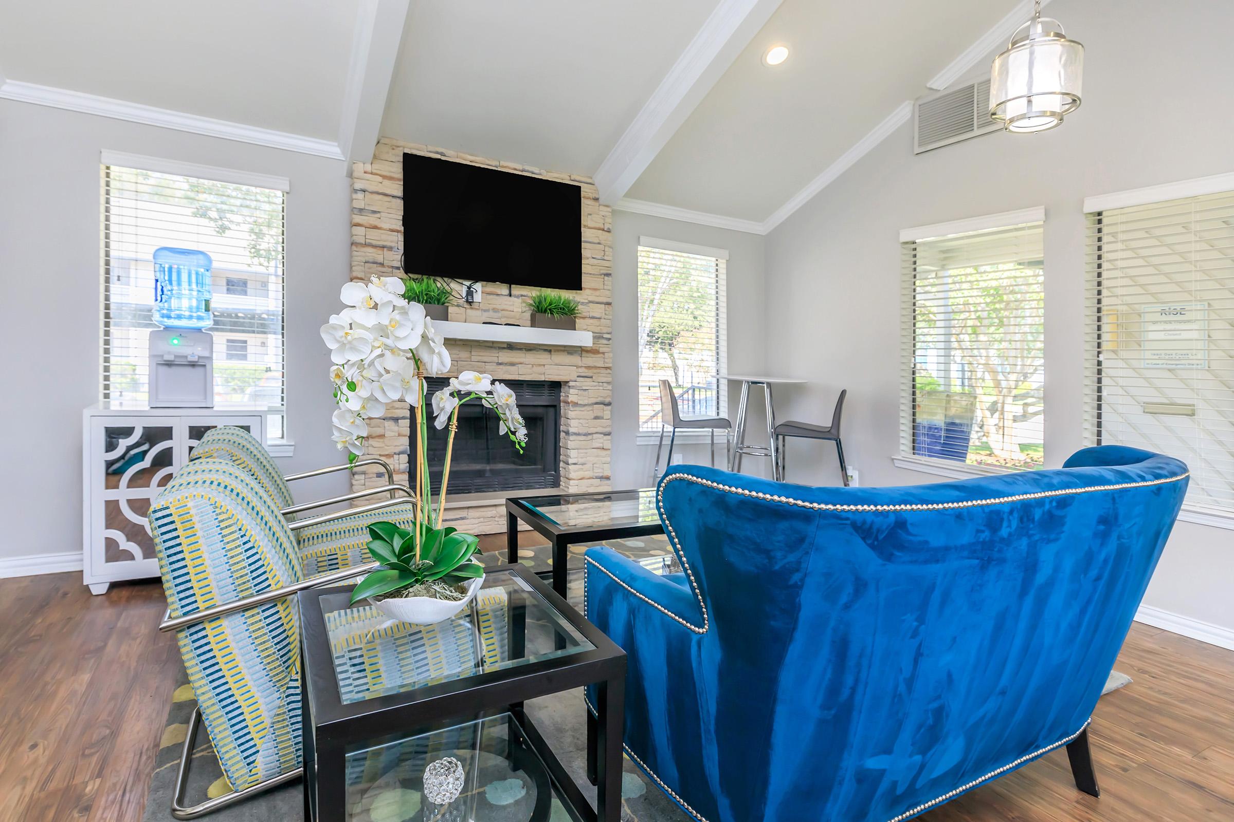 A living room with blue furniture and two windows are Rise Oak Creek.