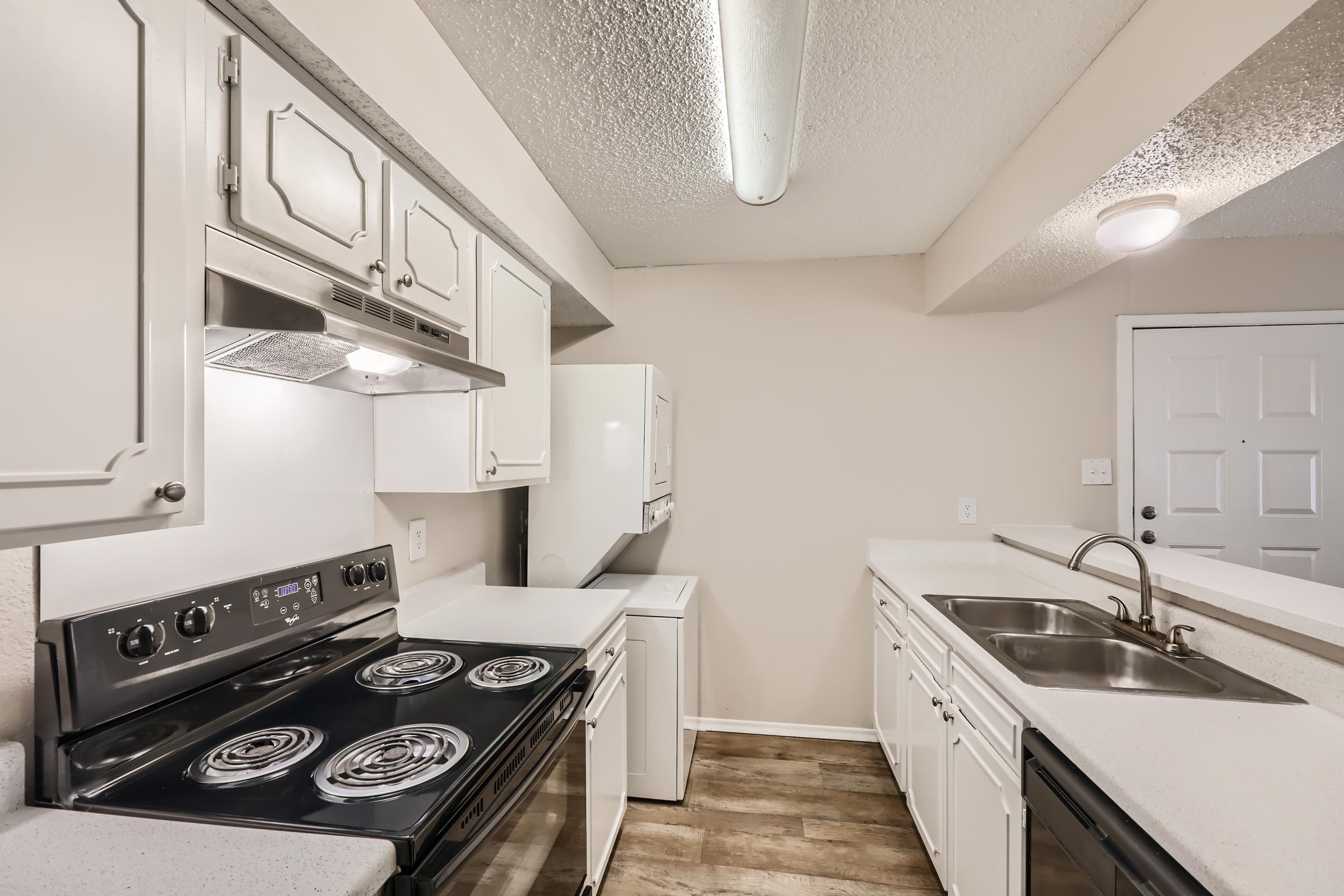 A kitchen with white cupboards and black appliances at Rise Oak Creek.
