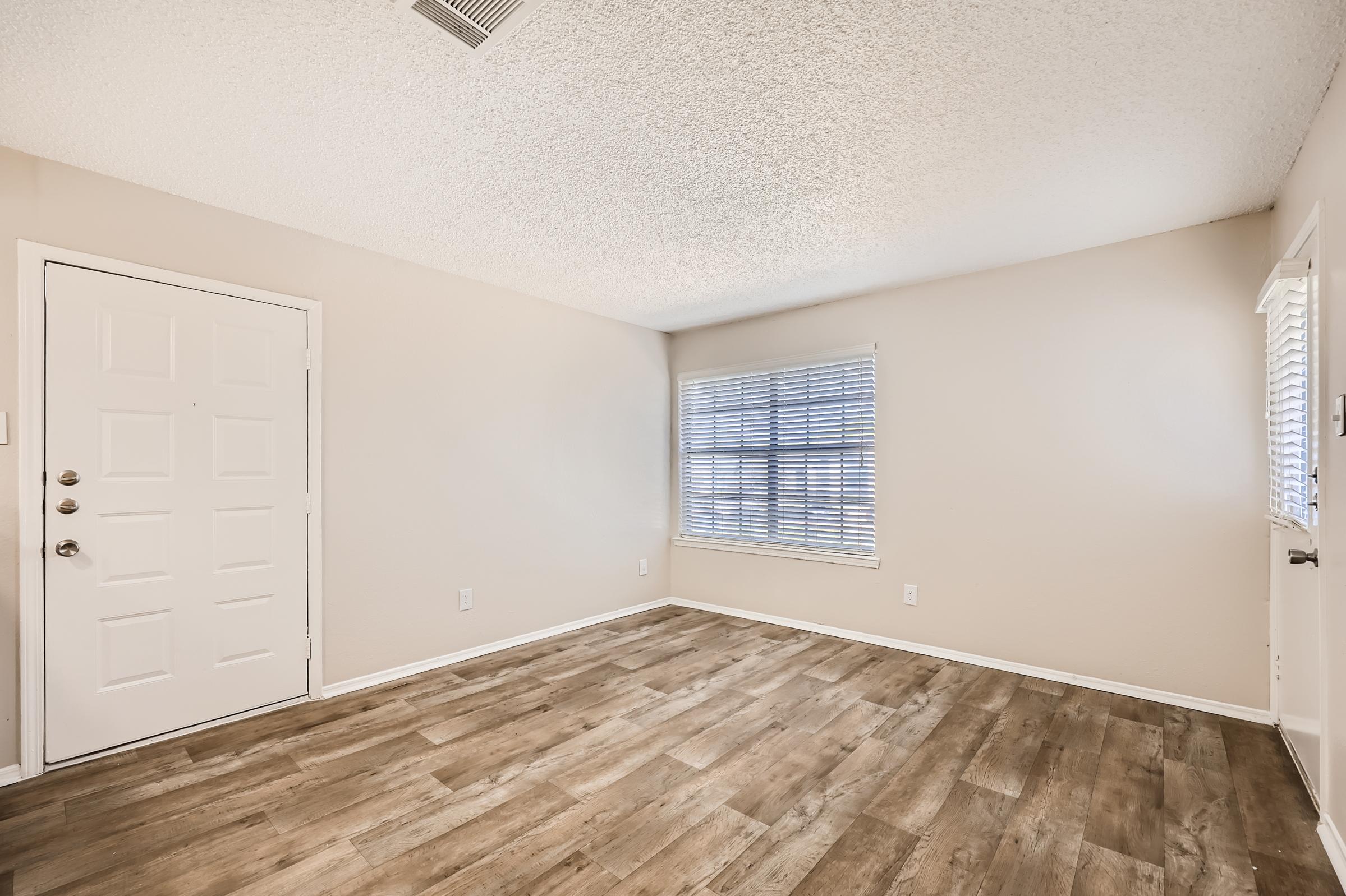 A living room with wood-style flooring and a window at Rise Oak Creek in Bedford, TX.