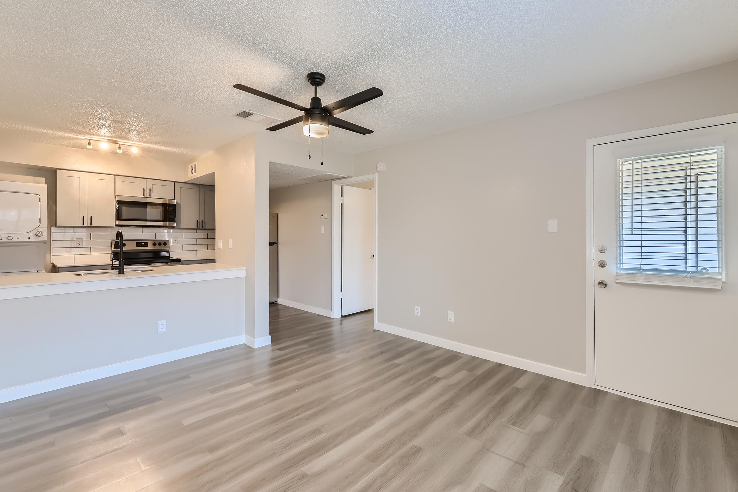 A large living room with a kitchen and a hallway to the bedrooms at Rise Oak Creek.