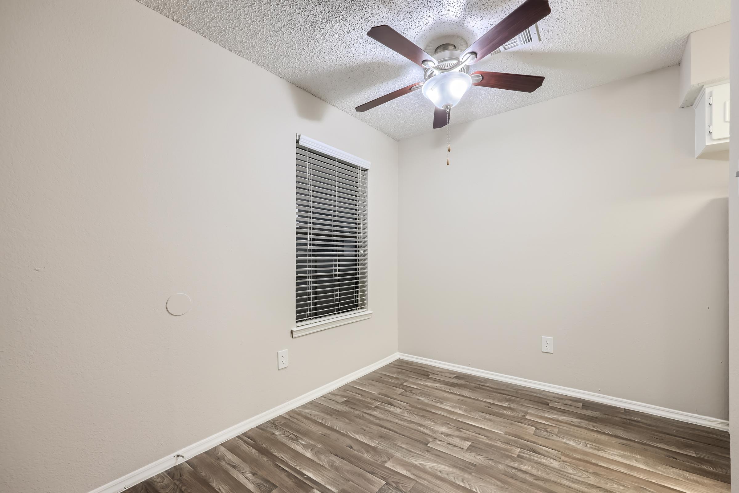 A small bedroom with wood-style floors, a ceiling fan and a window at Rise Oak Creek.