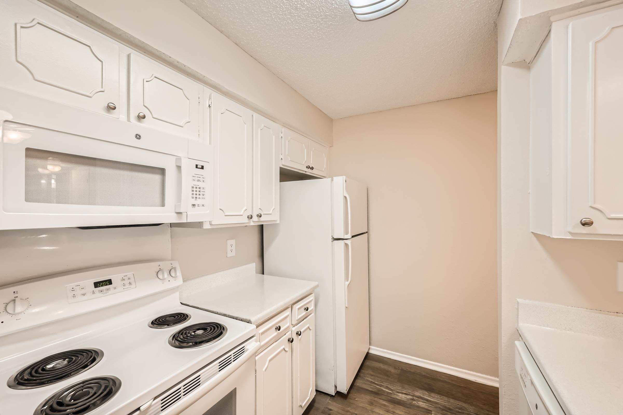A kitchen with white cupboards and white appliances at Rise Oak Creek.