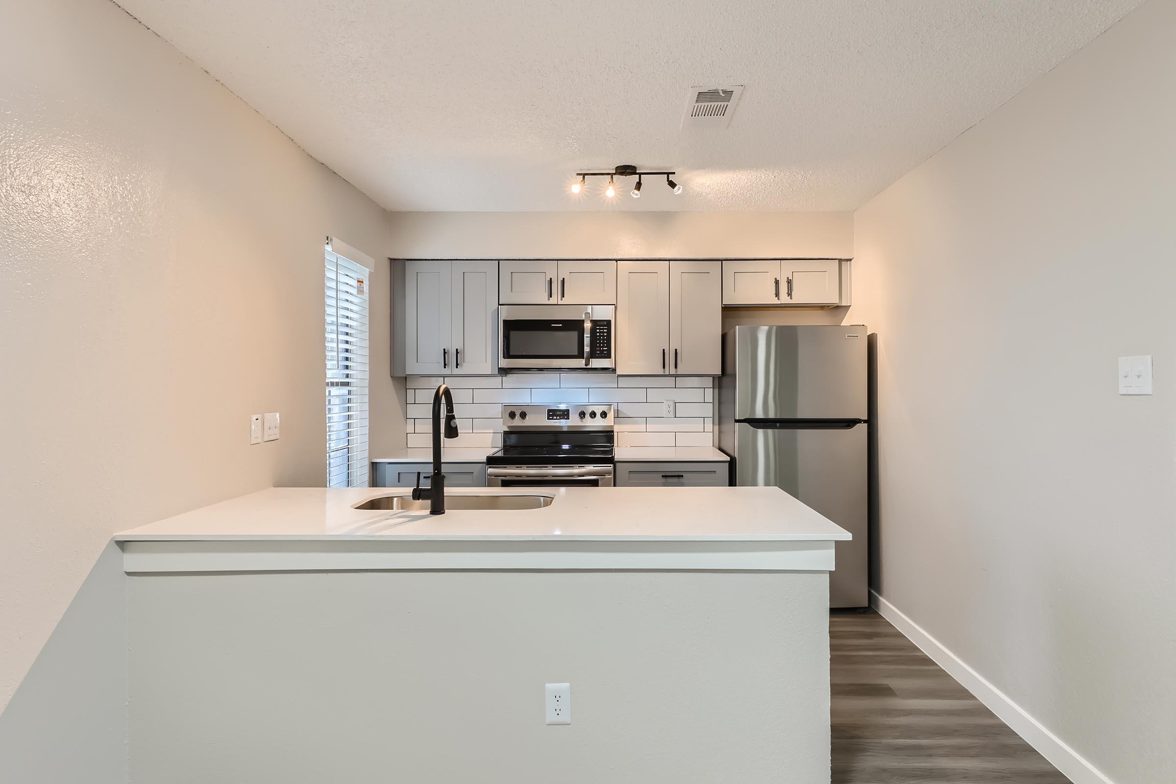 A kitchen with shaker cabinets and stainless steel appliances separated from the living space at Rise Oak Creek.