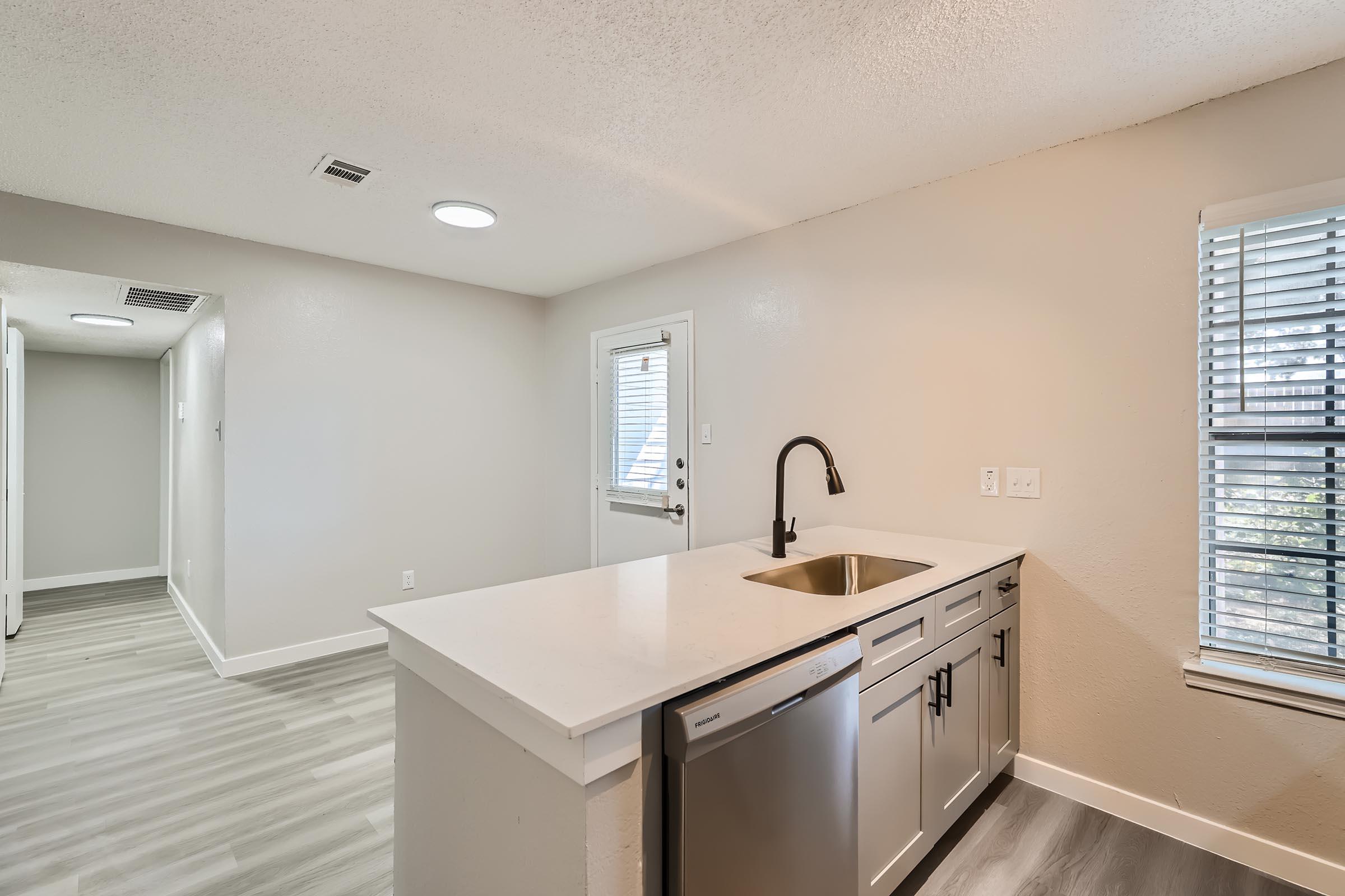 An apartment kitchen with a quartz countertop near the dining area at Rise Oak Creek.