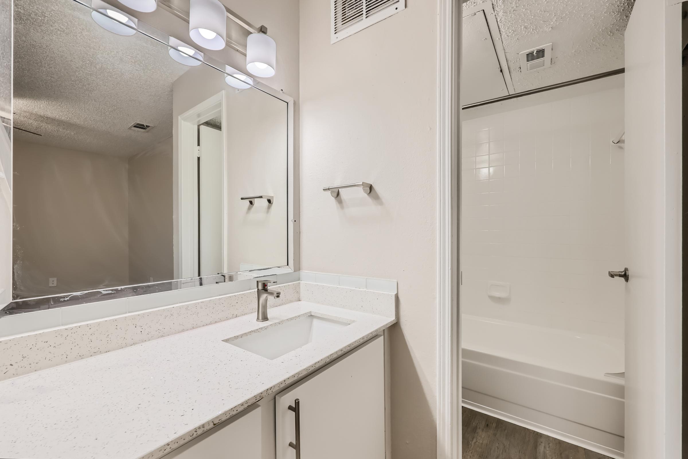 A bathroom with a separated shower and a vanity with quartz countertops at Rise Oak Creek.