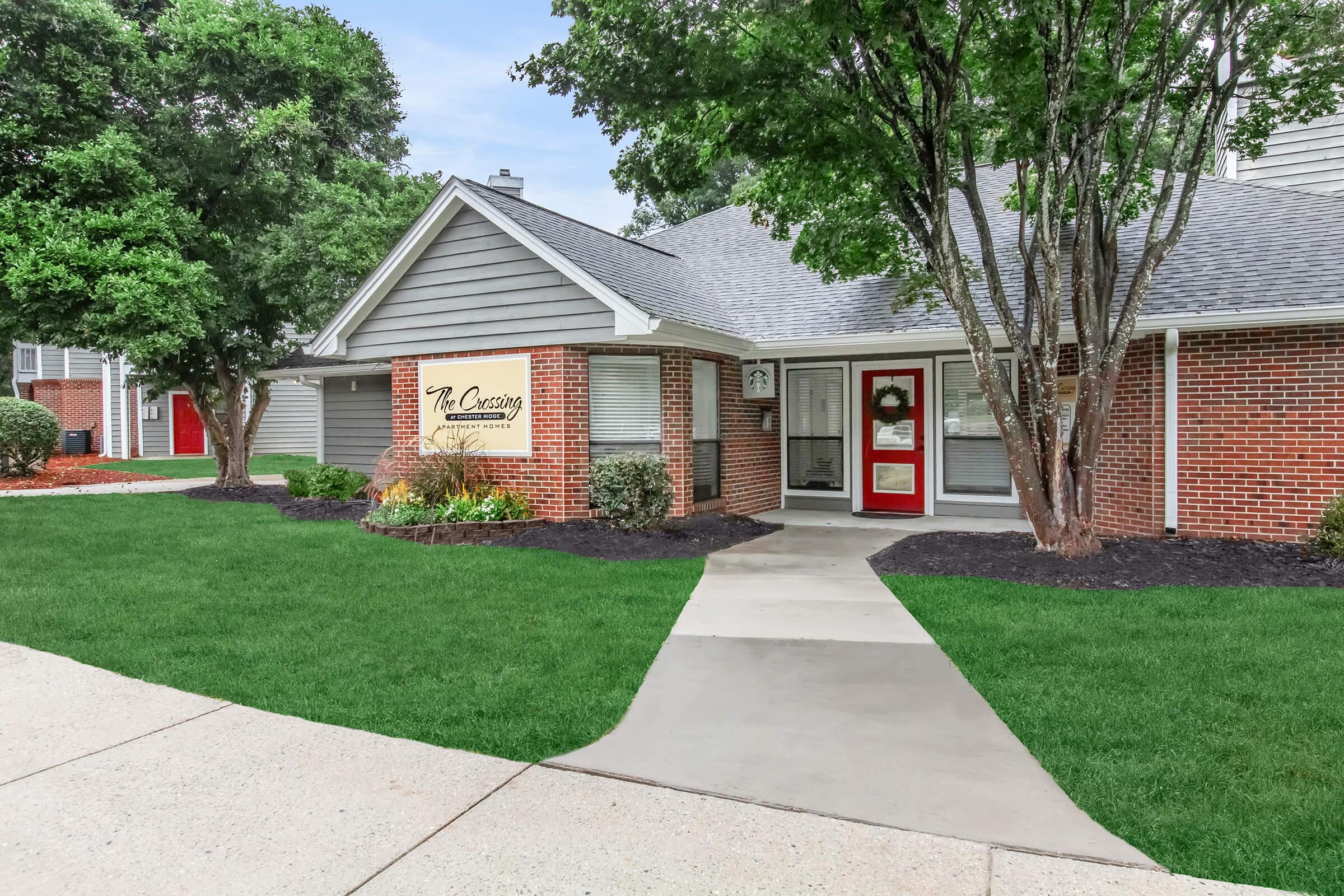 a house with a lawn in front of a brick building