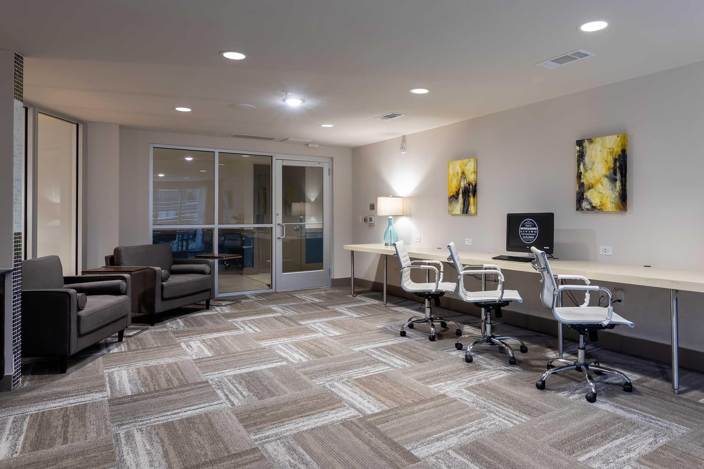 A modern office space with two ergonomic chairs and a large desk featuring a computer.