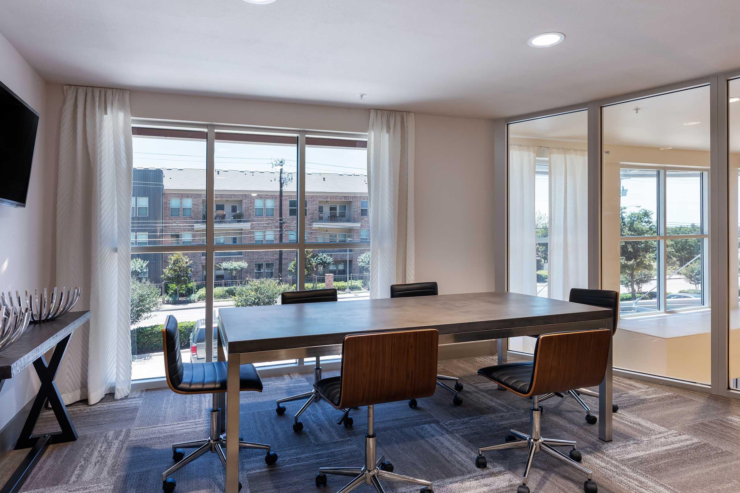 Modern conference room with a large table surrounded by black rolling chairs.