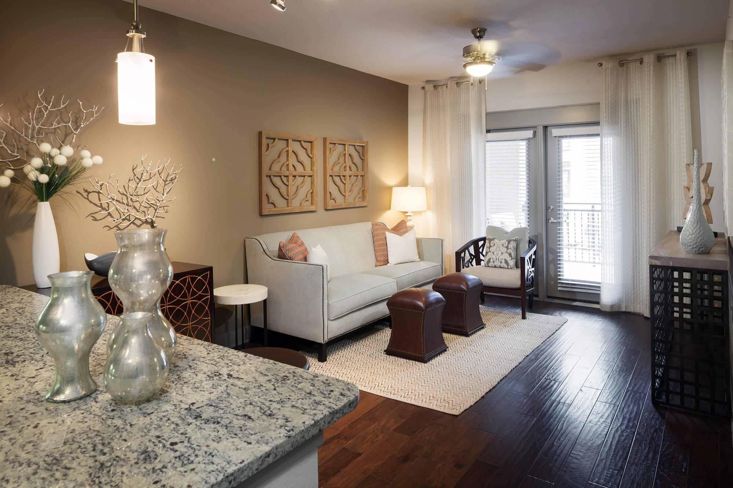 A modern living room featuring a light-colored sofa with decorative pillows, a coffee table, and stylish armchairs.