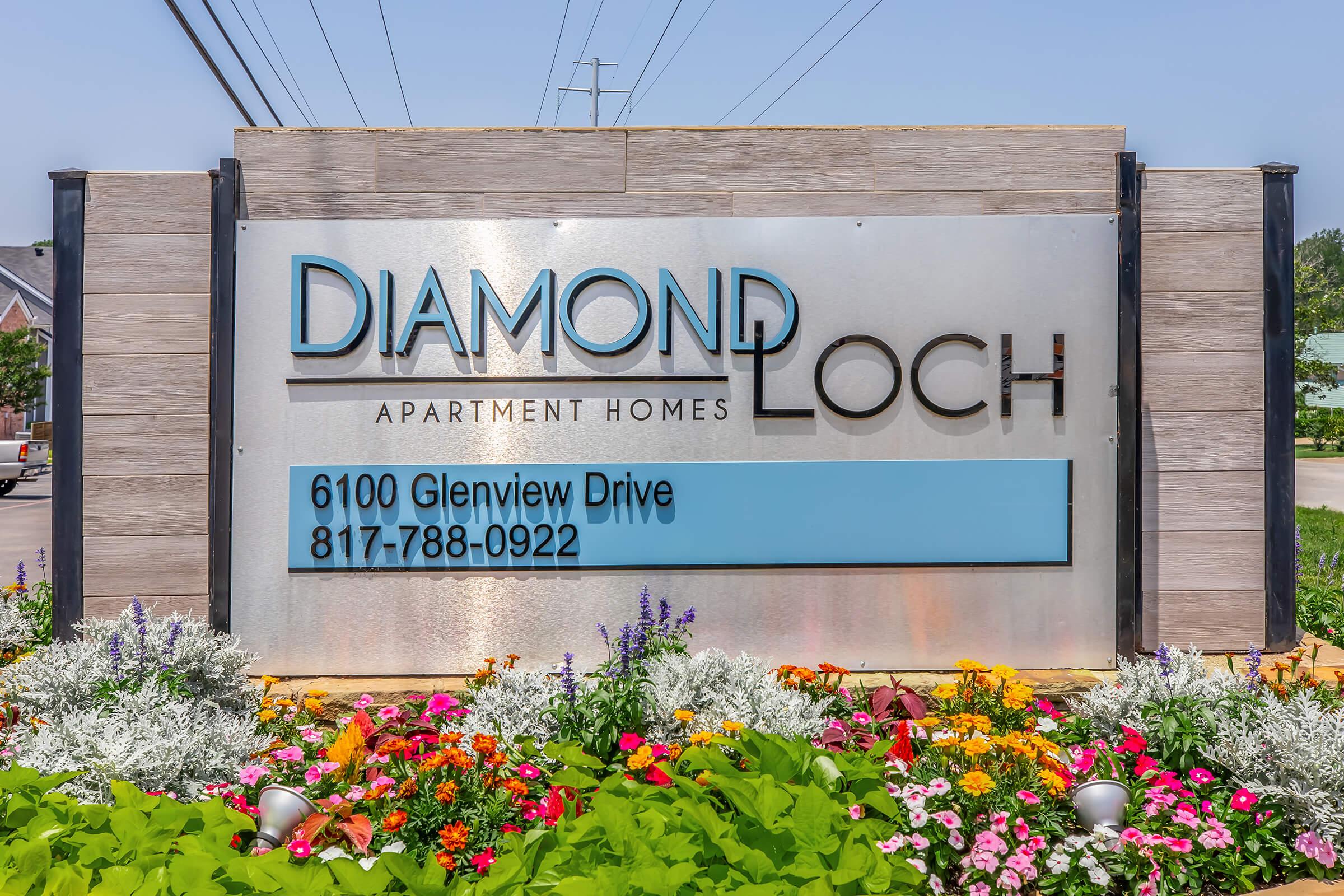 Sign for Diamond Loch Apartment Homes with the address 6100 Glenview Drive and phone number 817-788-0922, surrounded by colorful flowers and greenery.