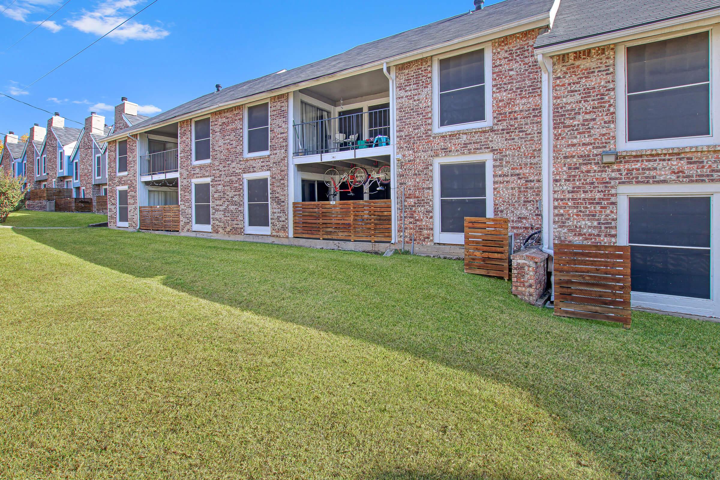 a large brick building with grass in front of a house