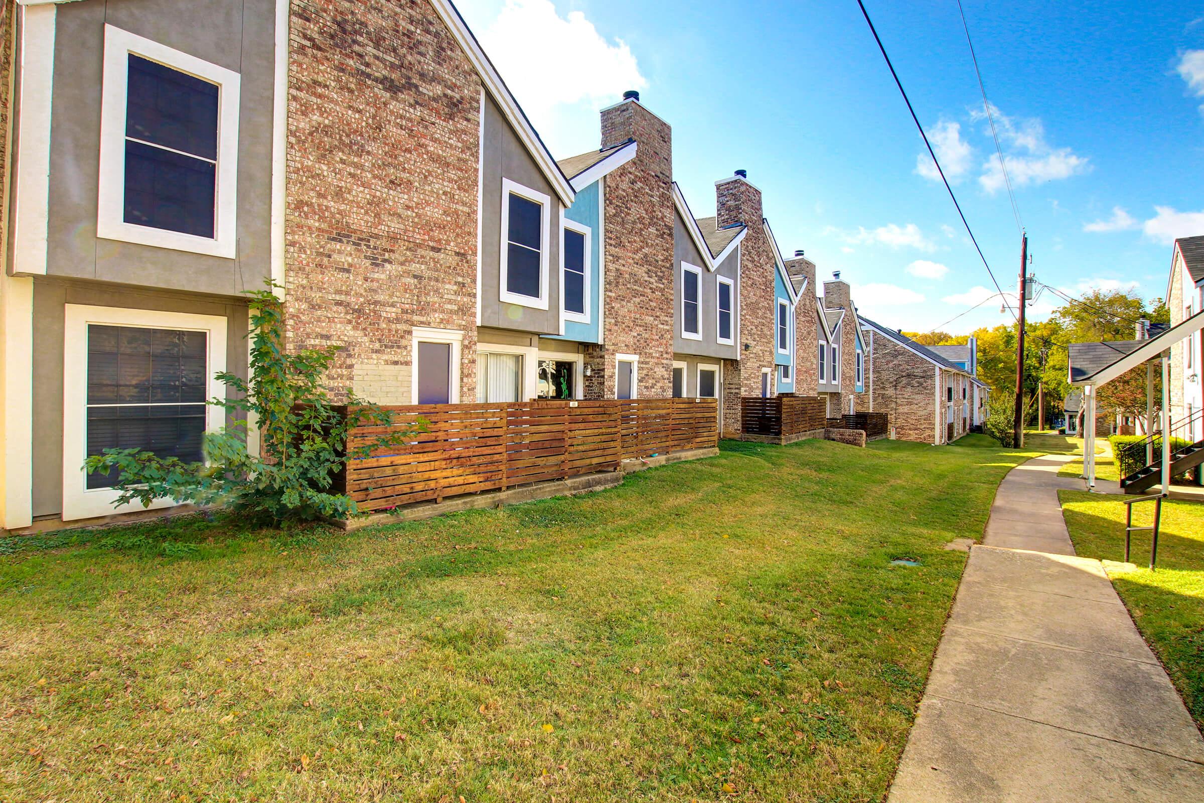 a large brick building with grass in front of a house