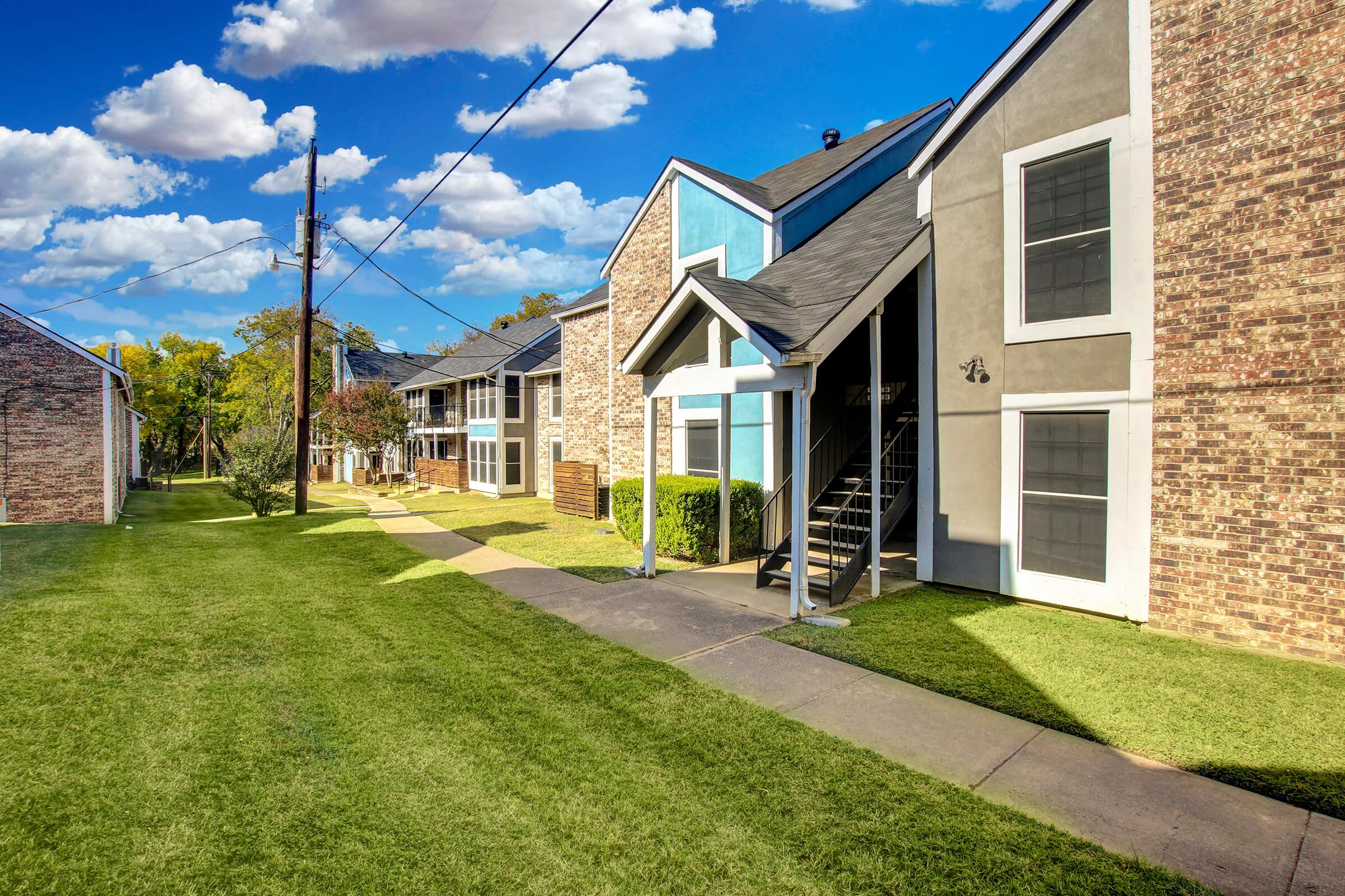 a large brick building with grass in front of a house